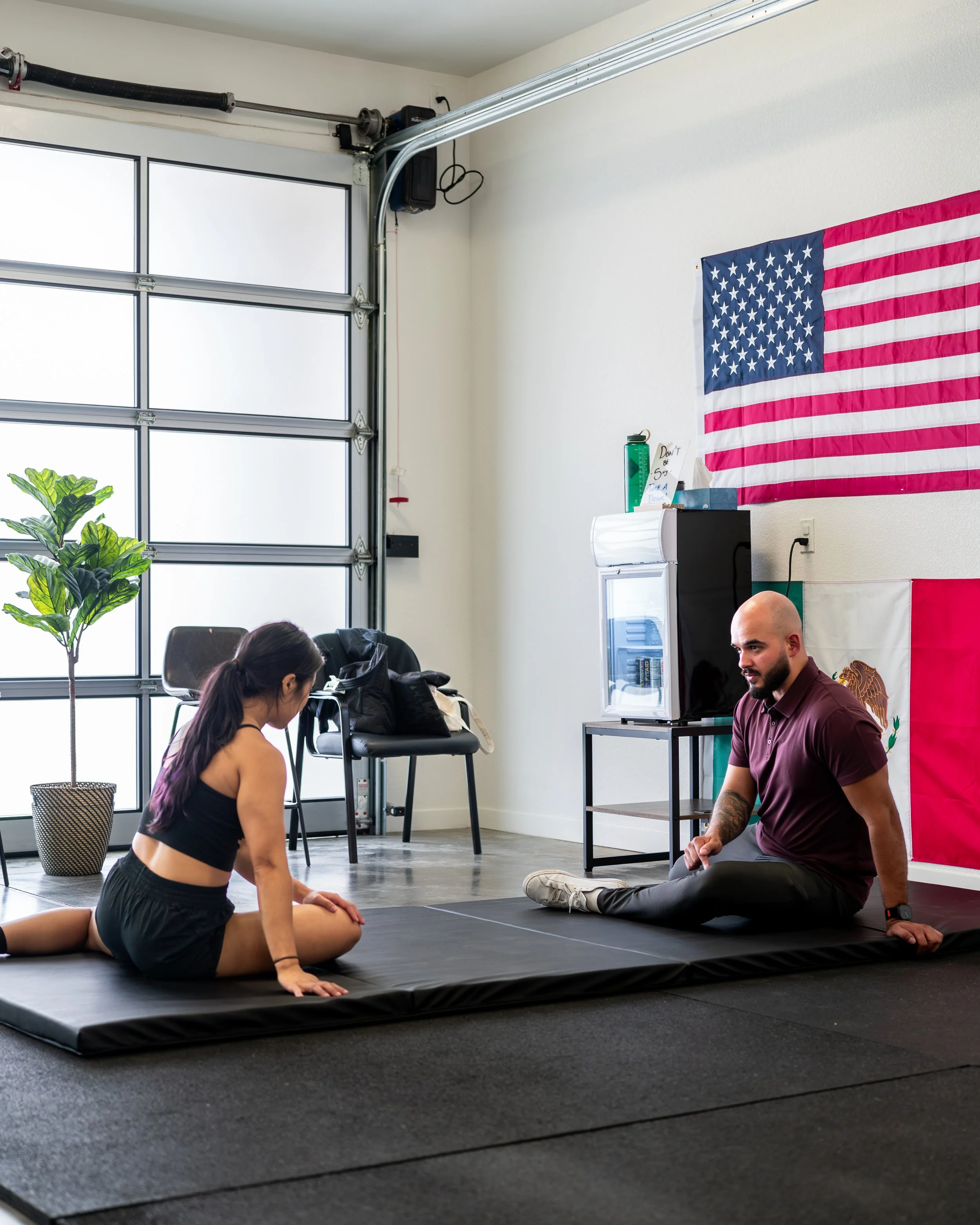 Dr. Carlos Padilla guiding a patient through mobility and stretching work at Ninety Four Performance & Rehab in Richmond, CA