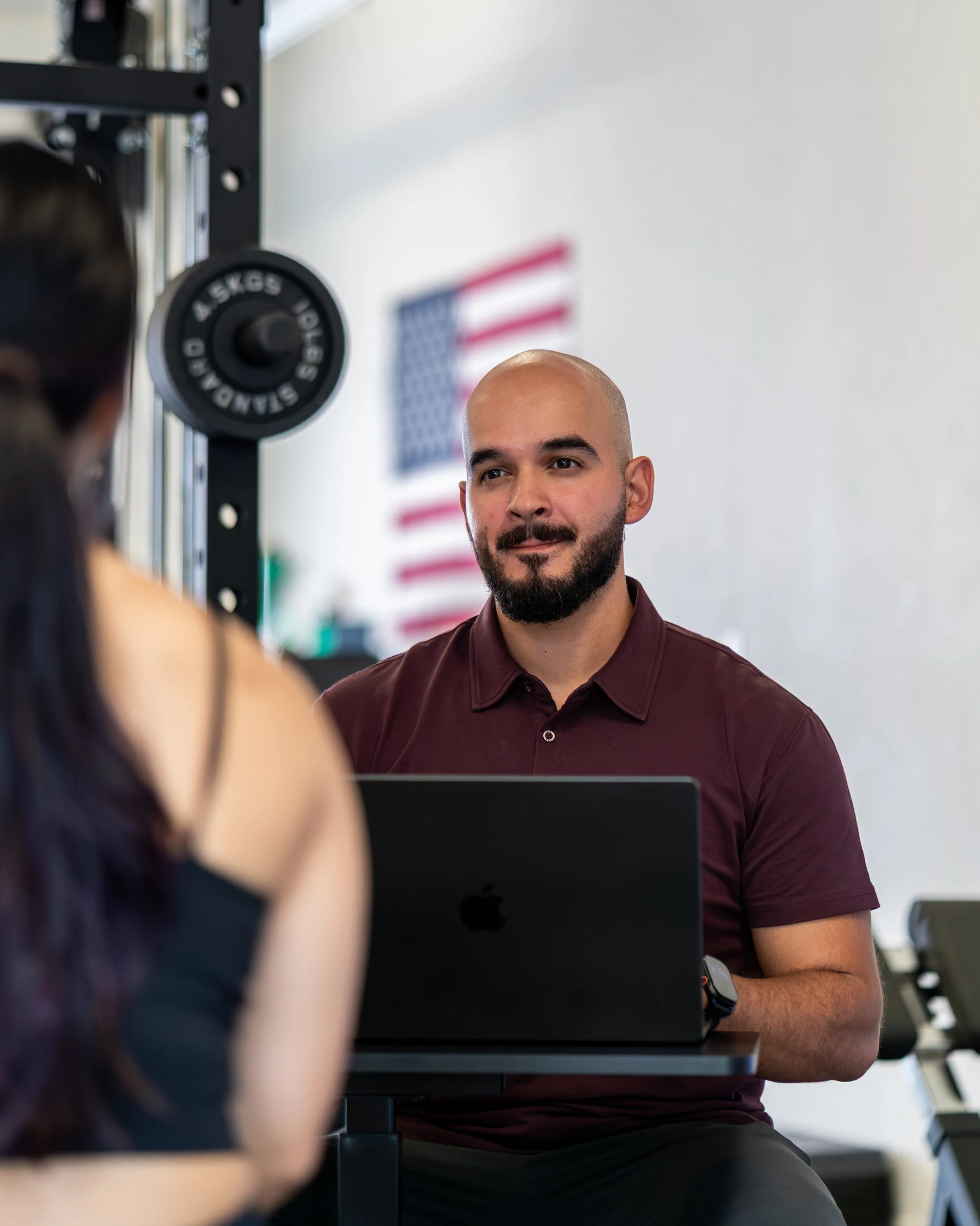 Dr. Carlos Padilla reviewing a patient's training program and checking in at Ninety Four Performance & Rehab in Richmond, CA