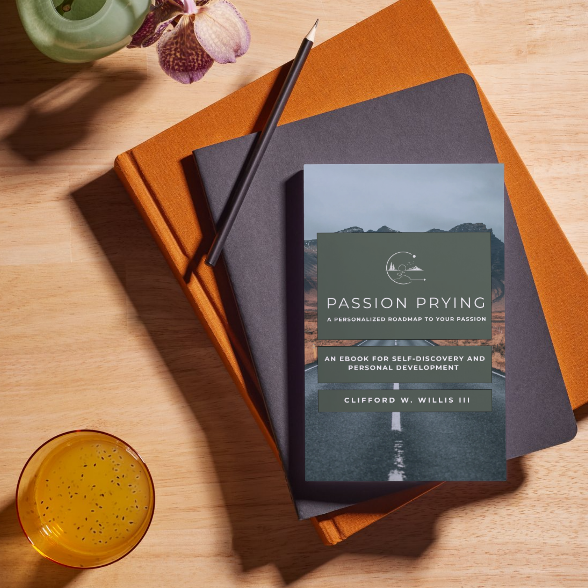Top view of a wooden table with an orange and a black book, a black pen, a purple orchid, a green vase, a small yellow cup, and a booklet titled Passion Prying.