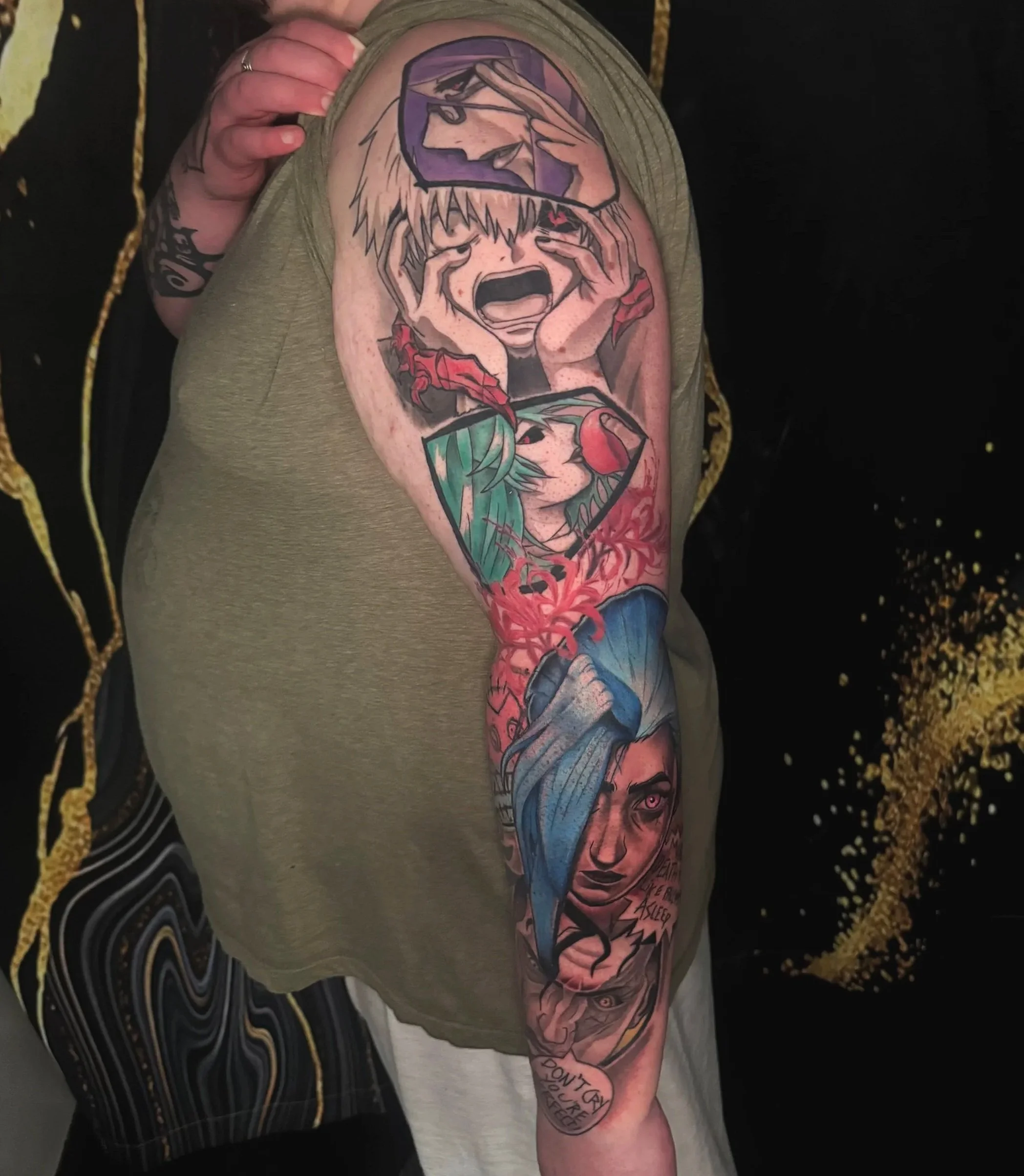 Colorful tattoo sleeve on person's arm featuring a crying woman with her hands on her face, surrounded by graphic designs and text.