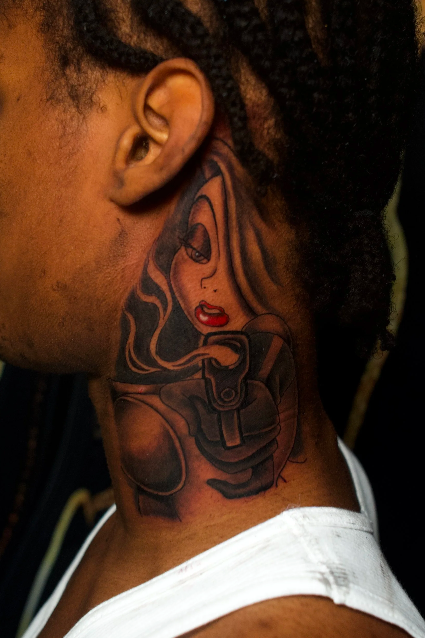 Close-up of a tattooed upper arm and shoulder with a woman’s face and red lipstick in tattoo art style.