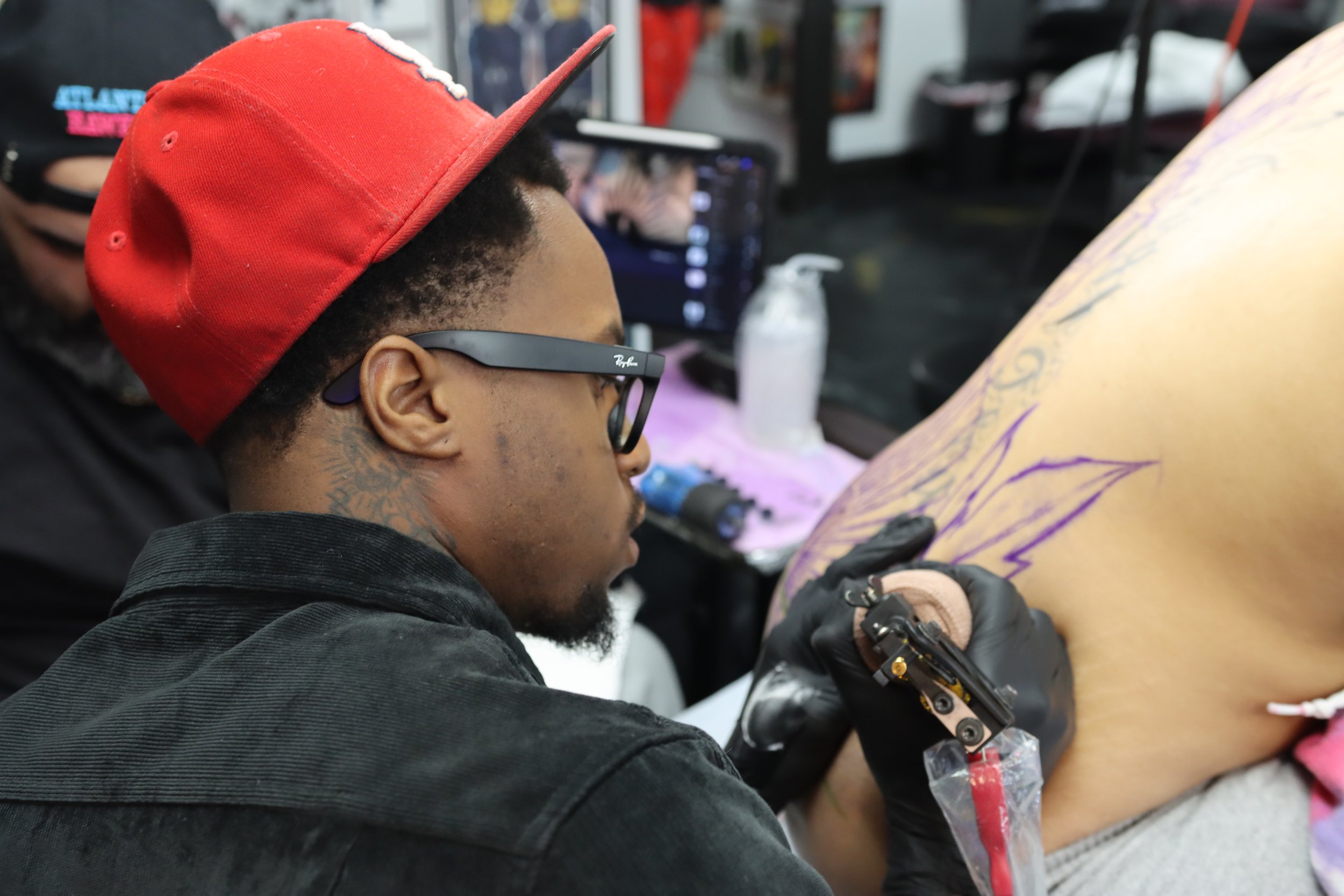 A person getting a tattoo on their leg in a tattoo shop, with a tattoo artist working on their skin.