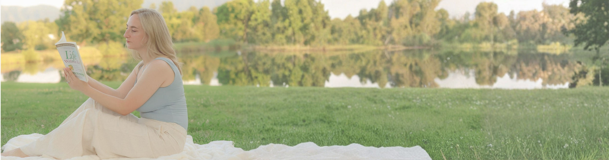 Teresa Kurth sitting on a picnic blanket by the water, reading a book beside the Blackbird Nutrition Therapy blog heading, “Let’s Make Nutrition Feel a Little Less Complicated.”