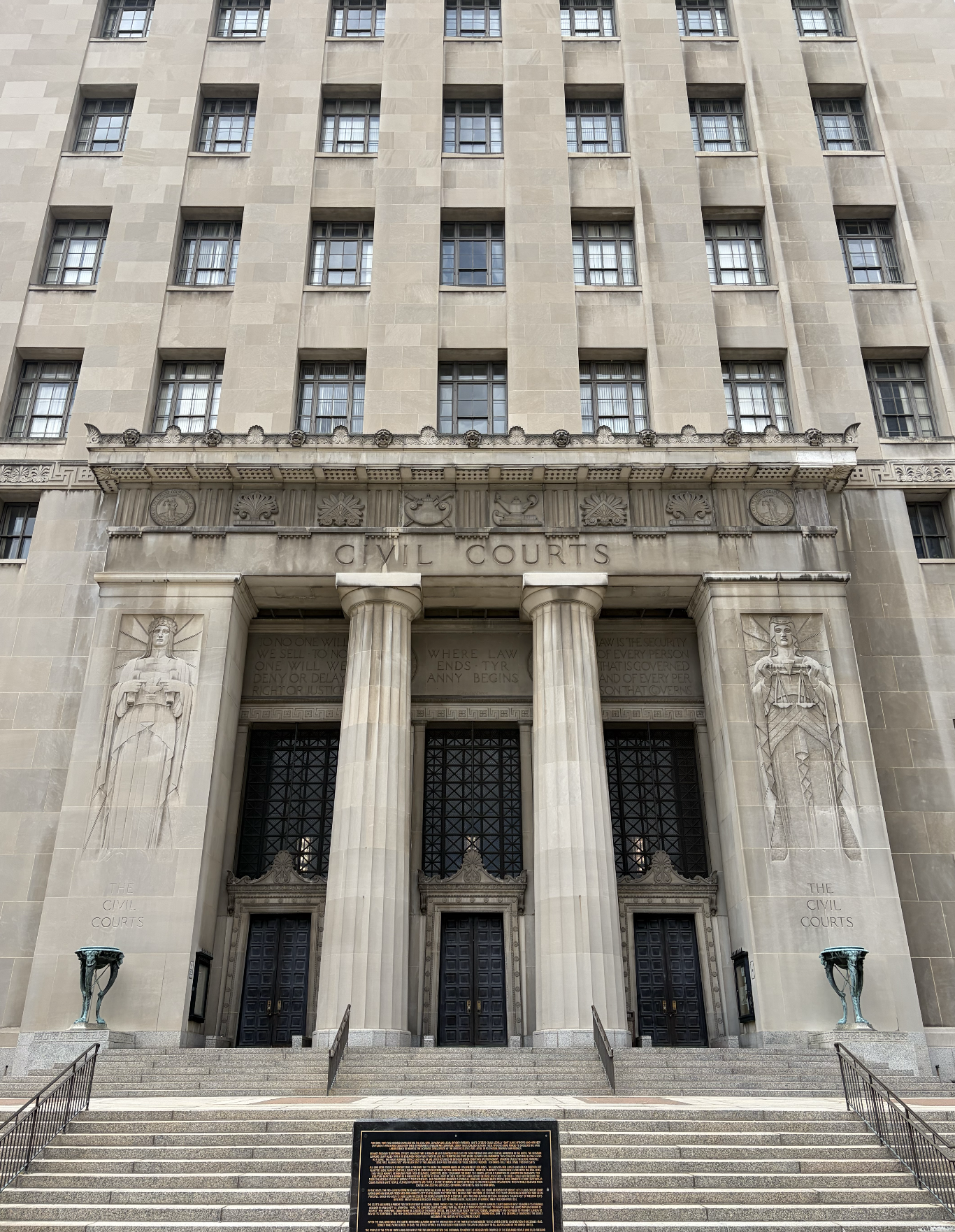 Front view of a historic government building labeled 'Civil Courts' with stone steps, two large columns flanking the entrance, statues, and decorative carvings.