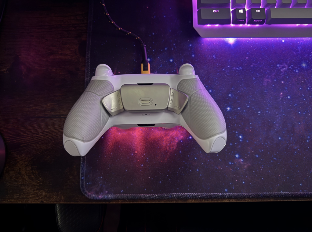 Western Edge Studios. A white gaming controller resting on a galaxy-themed mouse pad, with a purple-lit keyboard in the top right corner.