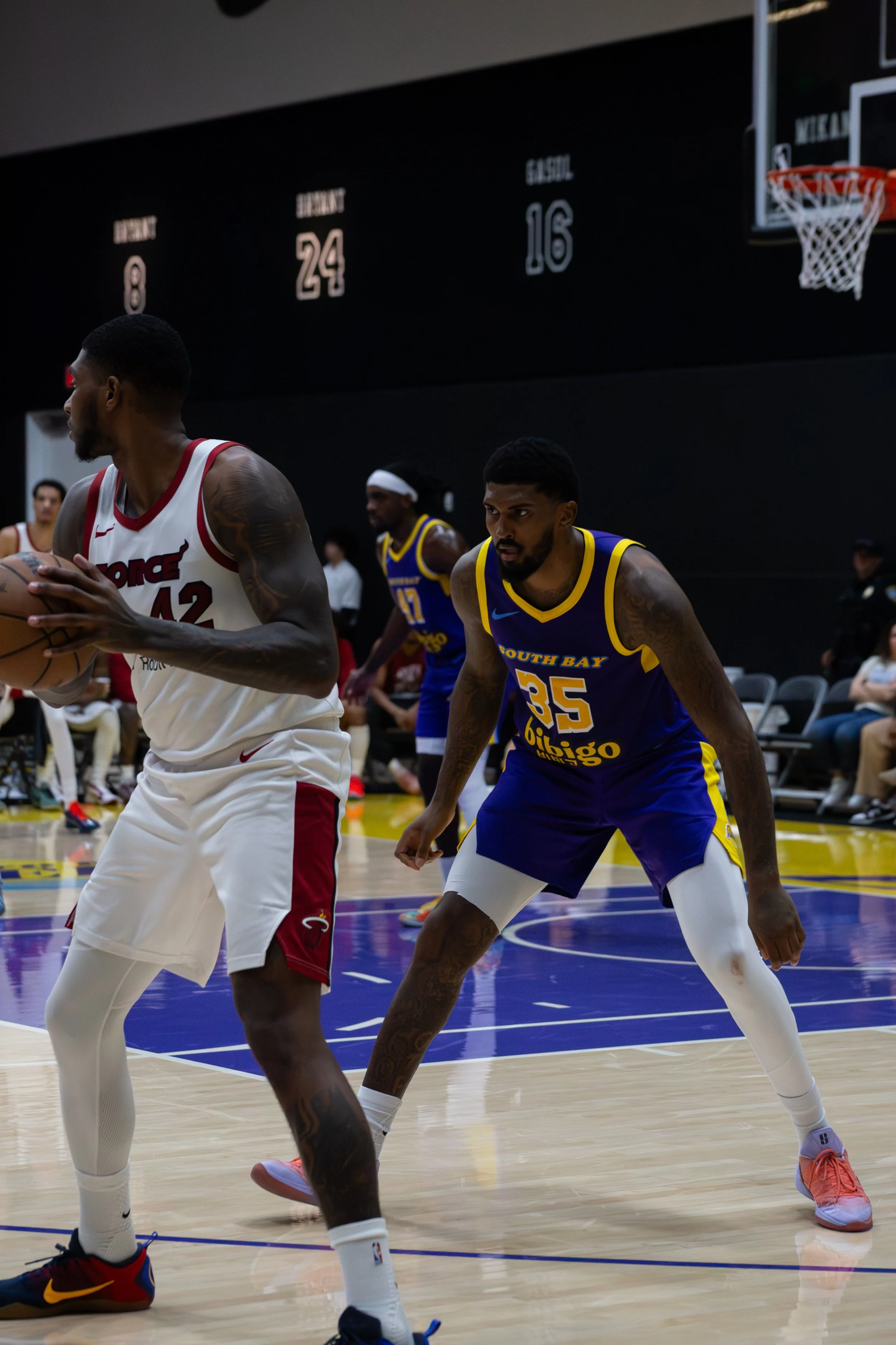 Two basketball players in blue and white uniforms playing defense against a player in a white and red Los Angeles Clippers uniform during a basketball game.