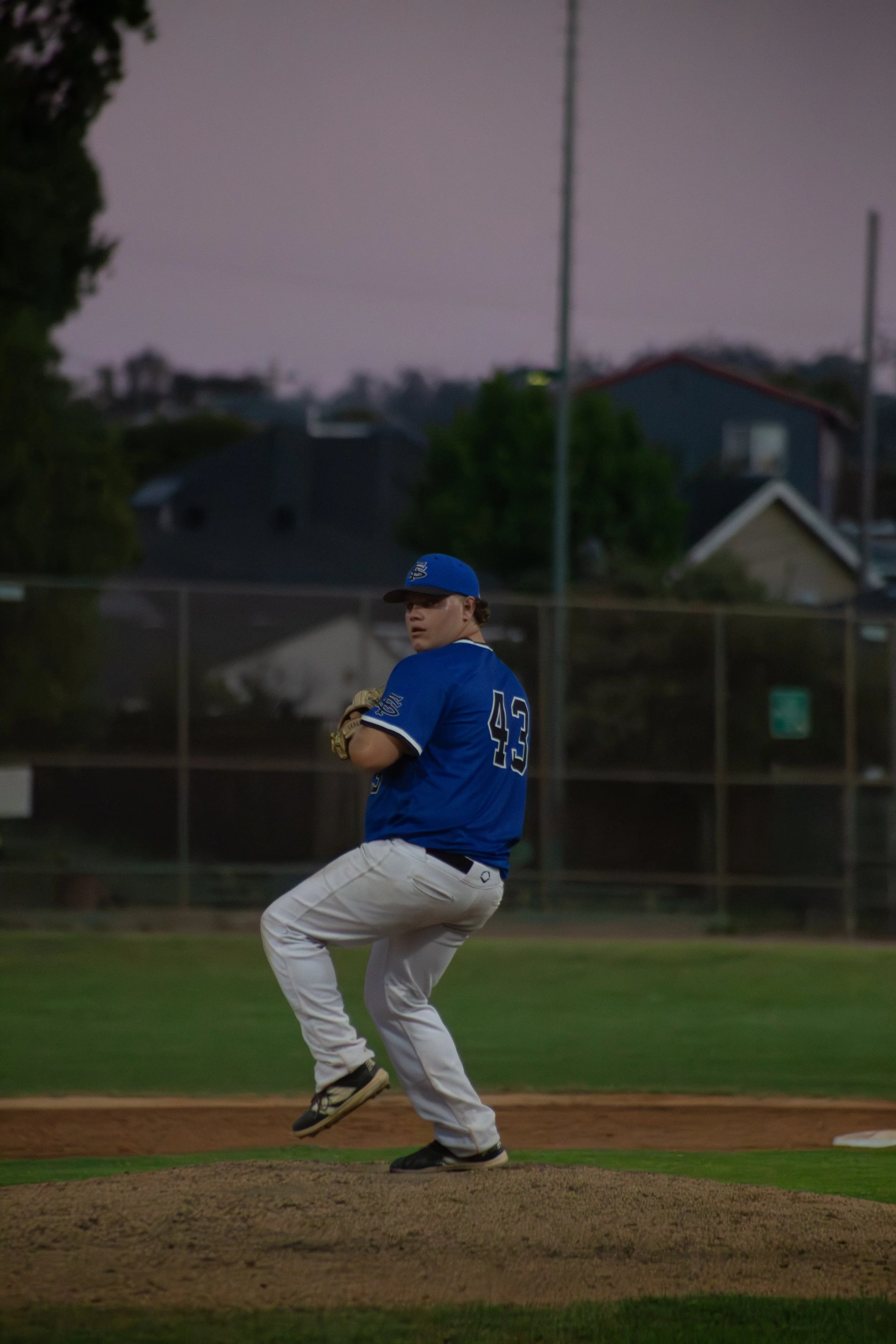 A baseball player in a blue jersey and white pants on the pitcher's mound during a game, preparing to pitch.
