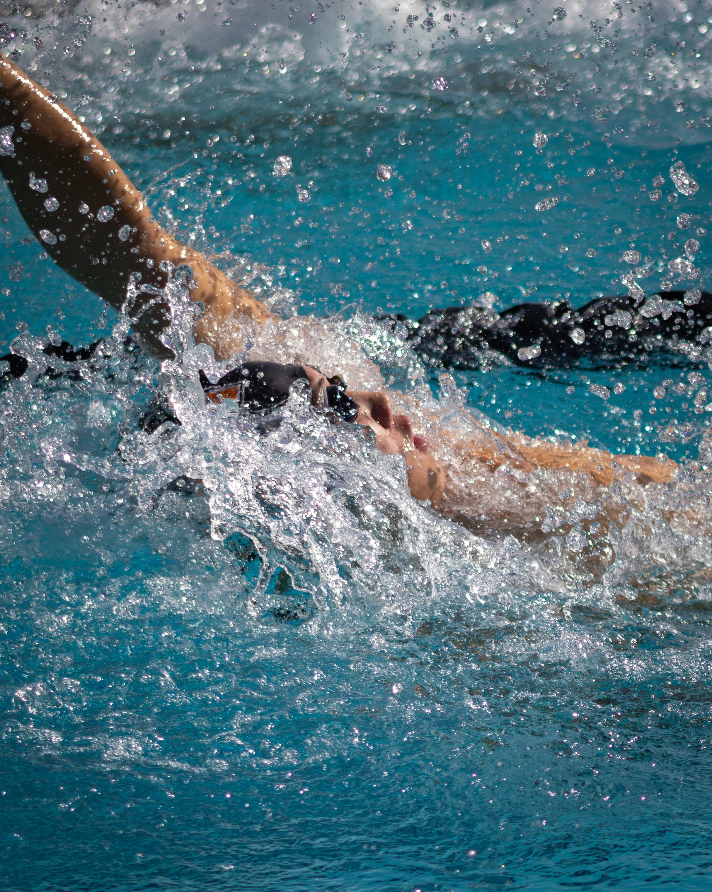 A person swimming in a pool, with water splashing around during a swim stroke.