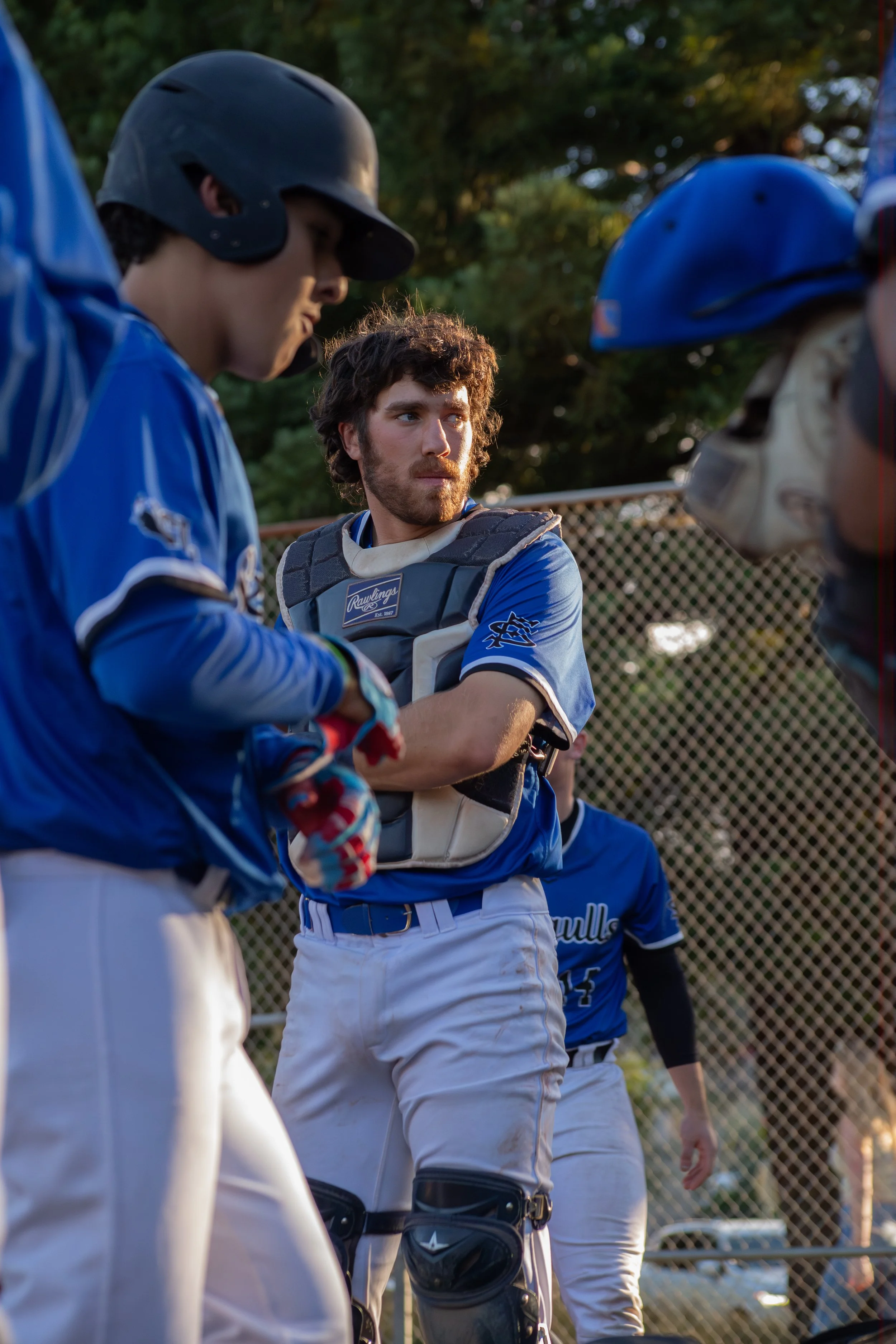 Baseball players wearing blue and white uniforms and helmets, standing on the field, listening to their coach during a game.