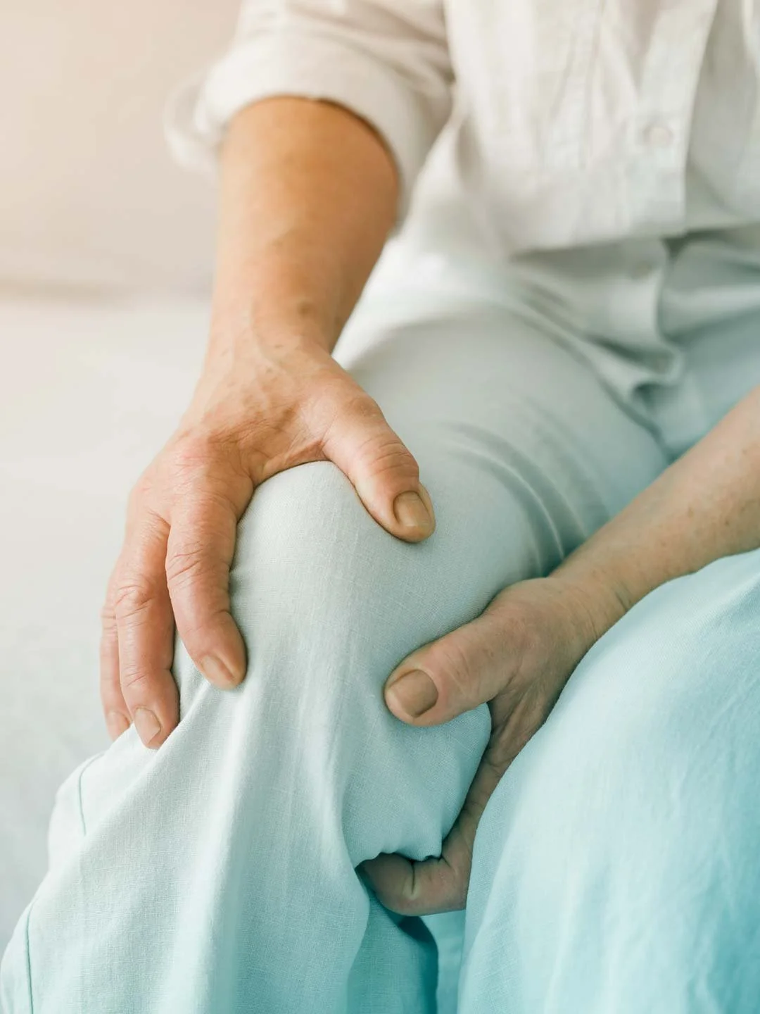 Persona mayor sosteniendo su rodilla con ambas manos.