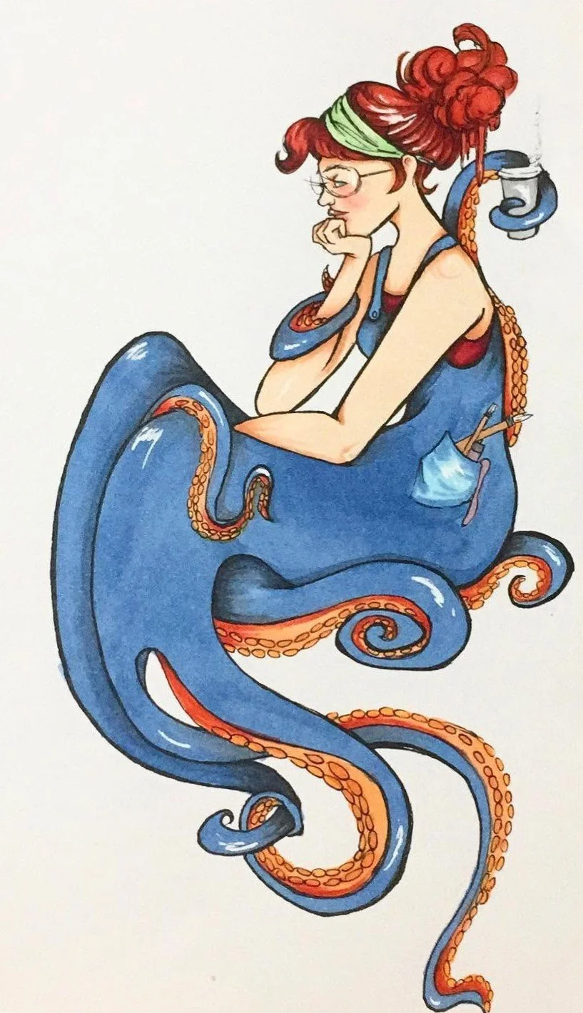 A woman with red hair, glasses, and a green headband as a blue octopus mermaid.