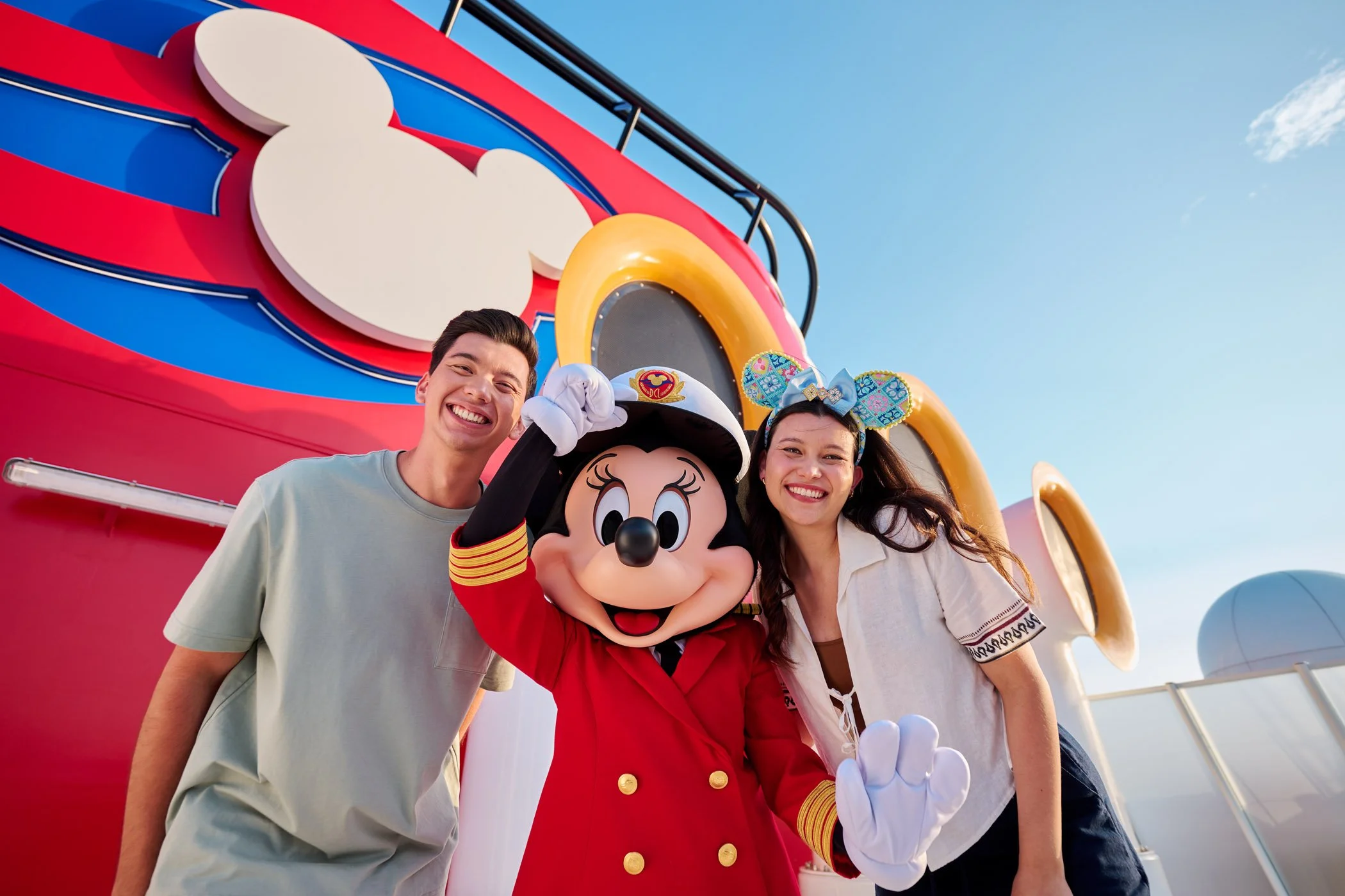 Two Disney Cruise passengers and Minnie Mouse posing together.
