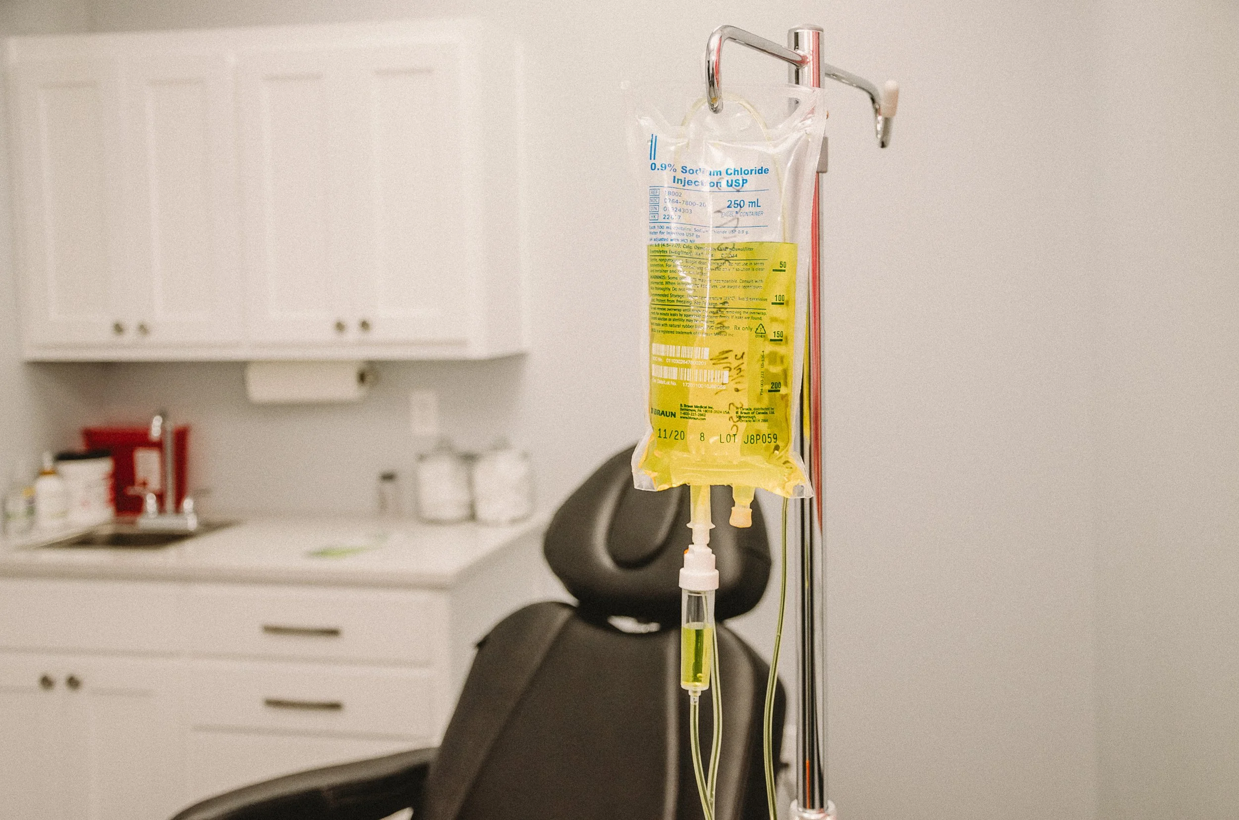 A hospital IV drip bag hanging on a pole in a medical examination room.