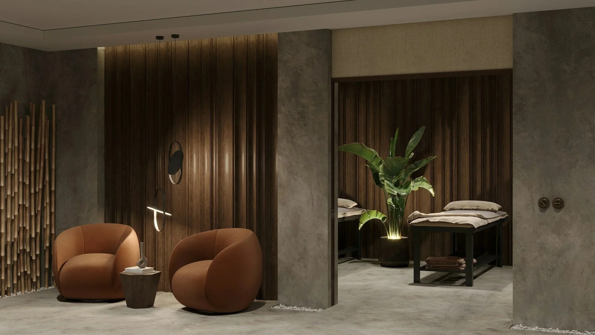 A modern interior space with two brown armchairs, a small side table with a sculpture, a large plant, and a section of a bedroom with a bed with beige bedding and navy bedside tables. The room has wood, concrete, and textured wall finishes.