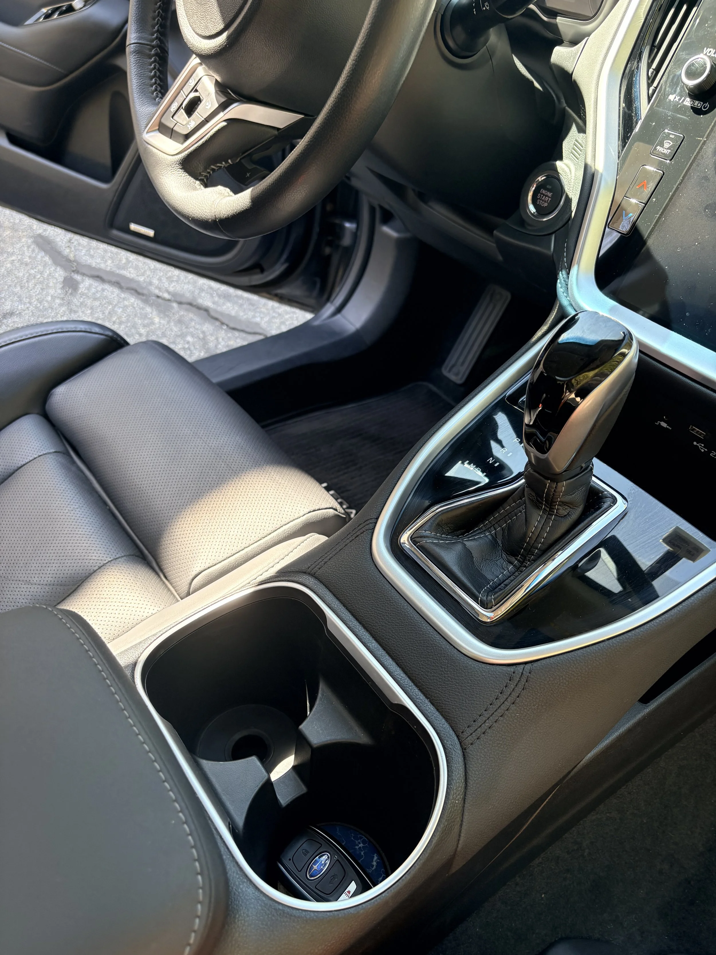 Interior of a car showing the center console with cup holders, gear shift, and key fob, along with part of the steering wheel and dashboard.