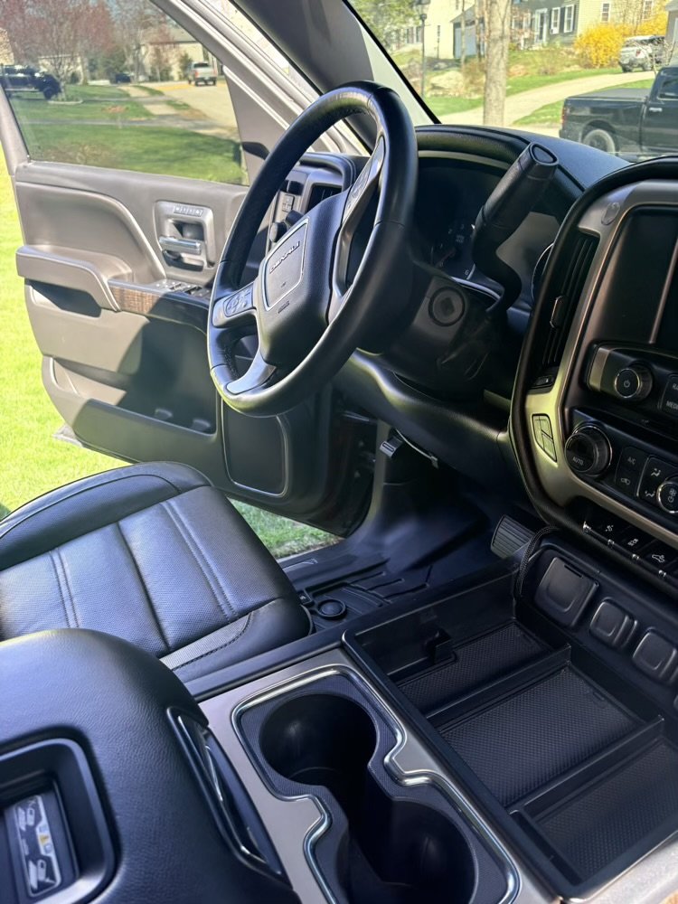 Interior view of a truck's driver's side, showing the steering wheel, dashboard, and center console with cup holders and storage compartments.