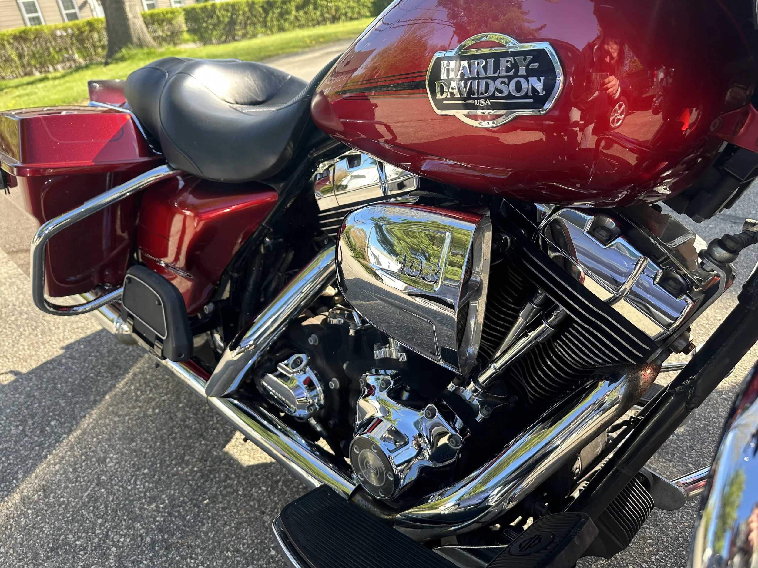 A close-up of a red Harley-Davidson motorcycle with chrome details, a black leather seat, and a shiny fuel tank.