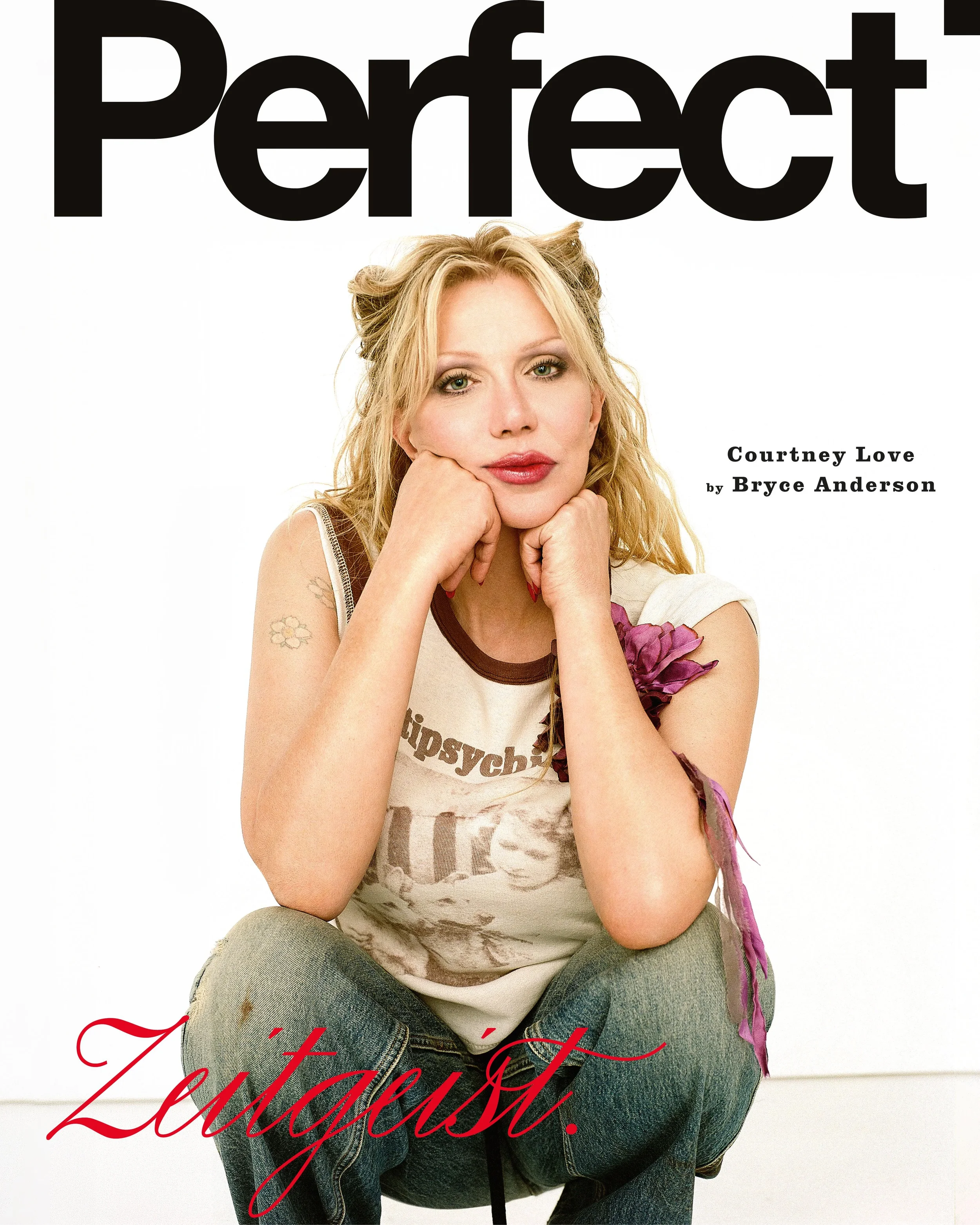 Cover of a magazine featuring a woman with blonde hair, sitting with her knees up, wearing a beige t-shirt with printed text and ripped jeans, resting her chin on her hands, with text overlaid reading 'Perfect' at the top and 'Juxtaposition' in red c
