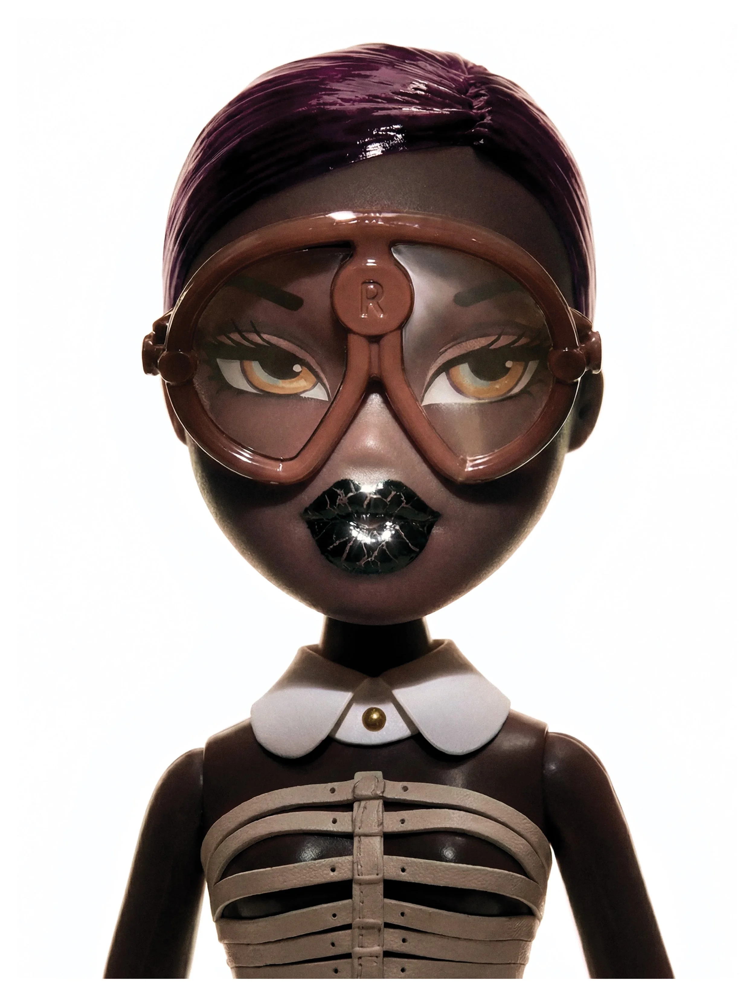 A doll with painted brown skin wearing brown glasses, black lipstick, a white collar, and a black and white skeleton torso.
