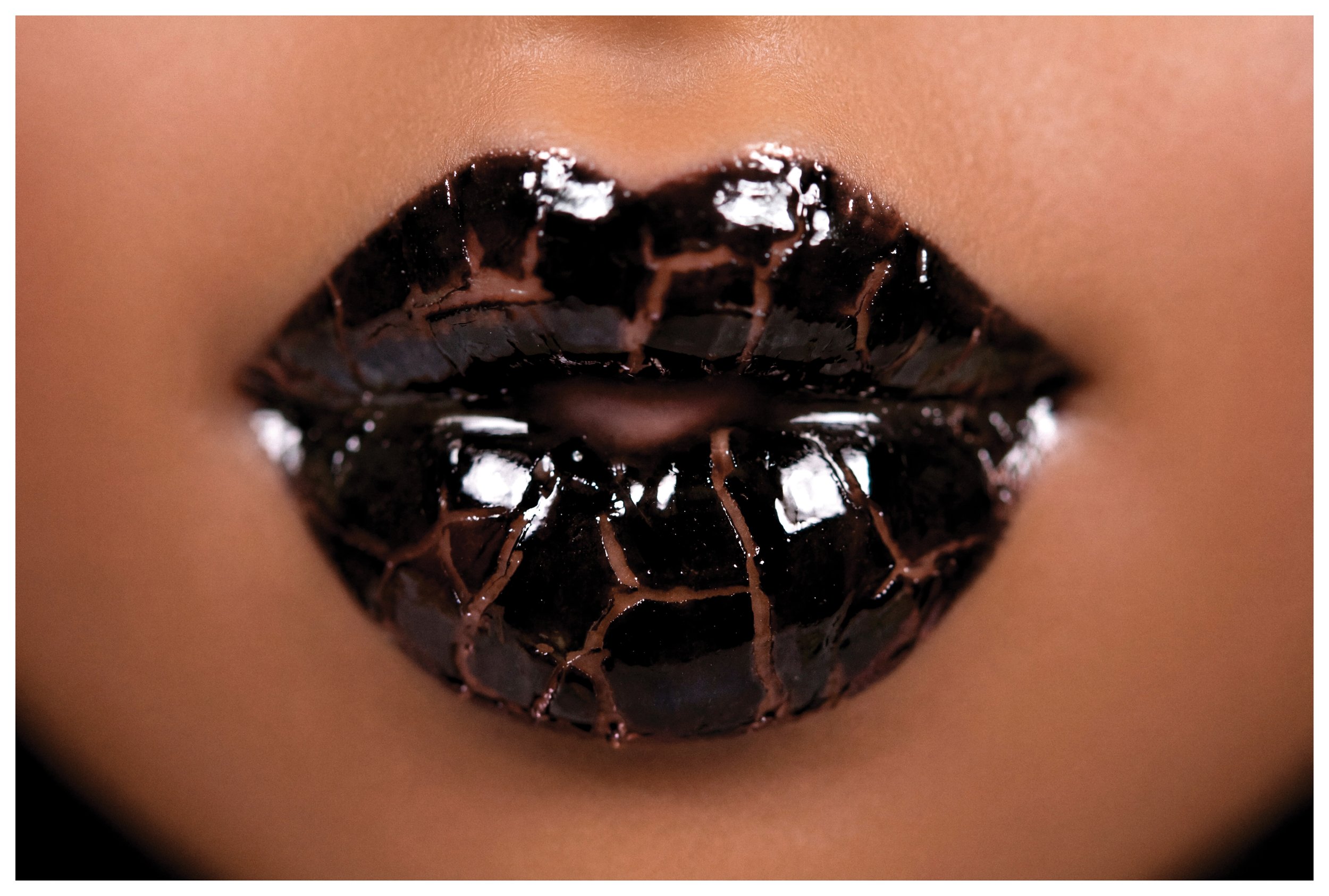 Close-up of lips with black gloss lipstick, with a smooth skin tone in the background.