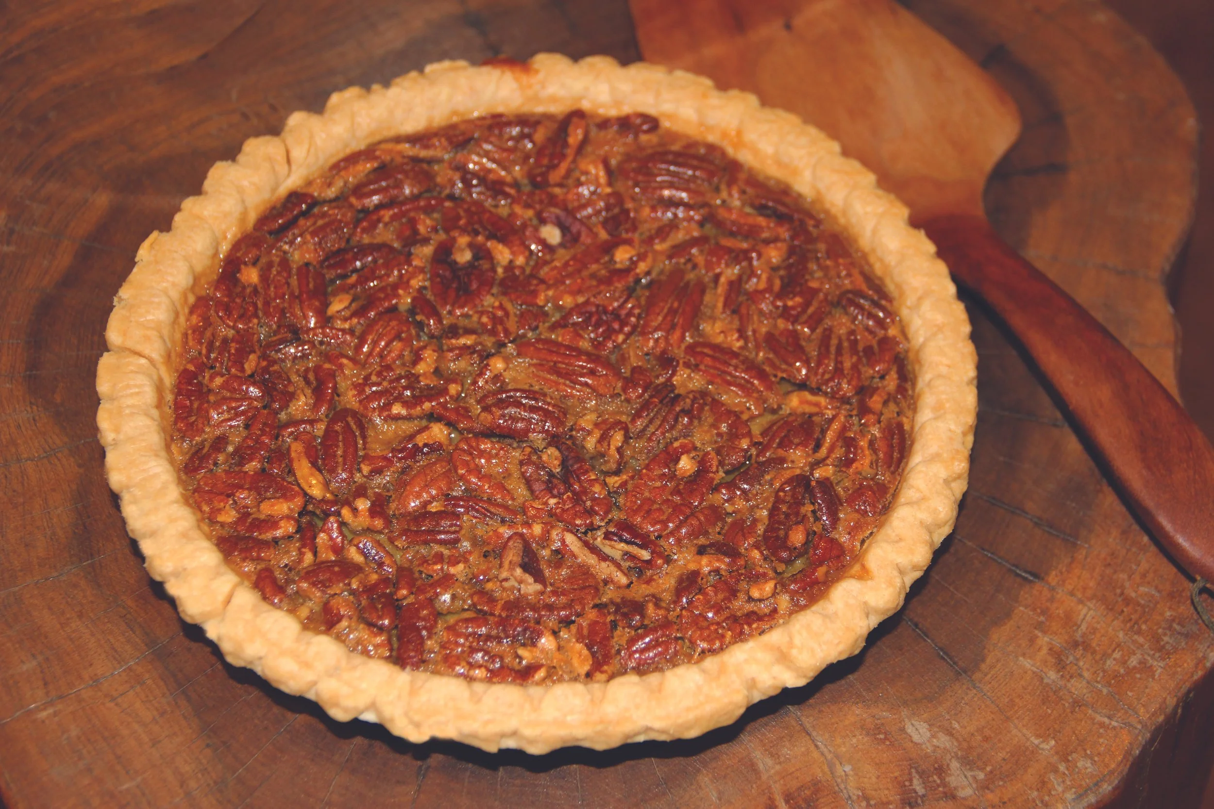 A pecan pie with a golden crust on a wooden surface.