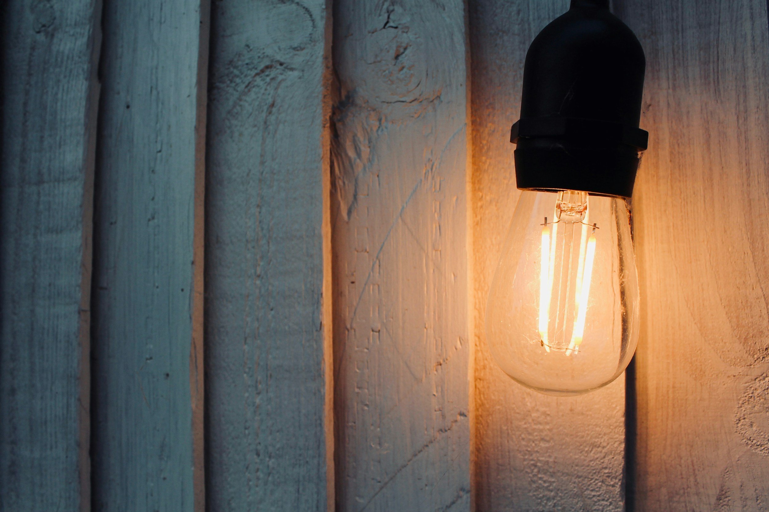 Ampoule électrique lumineuse fixée au mur en bois, éclairant doucement la surface en dessous.