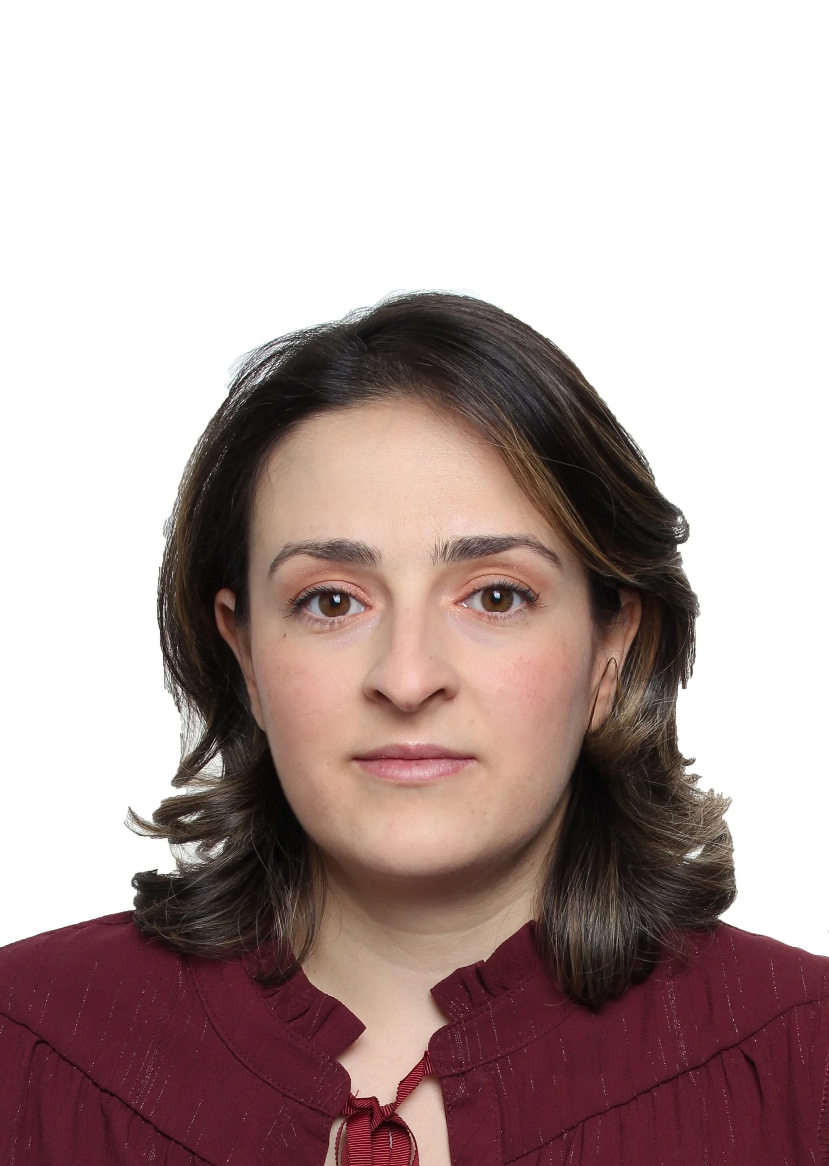Photo en gros plan d'une femme avec des cheveux bruns bouclés et courts, portant un haut rouge avec un col à lacet, contre un fond blanc.