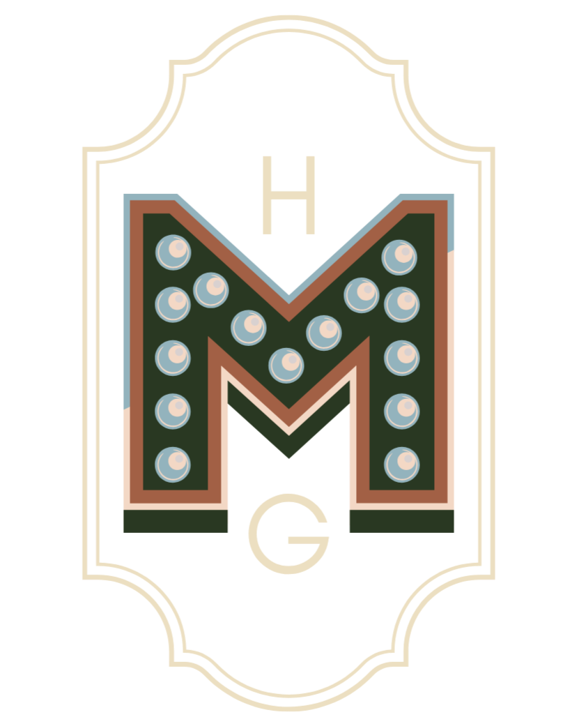 Colorful marquee letter 'M' with light bulbs on a decorative background.
