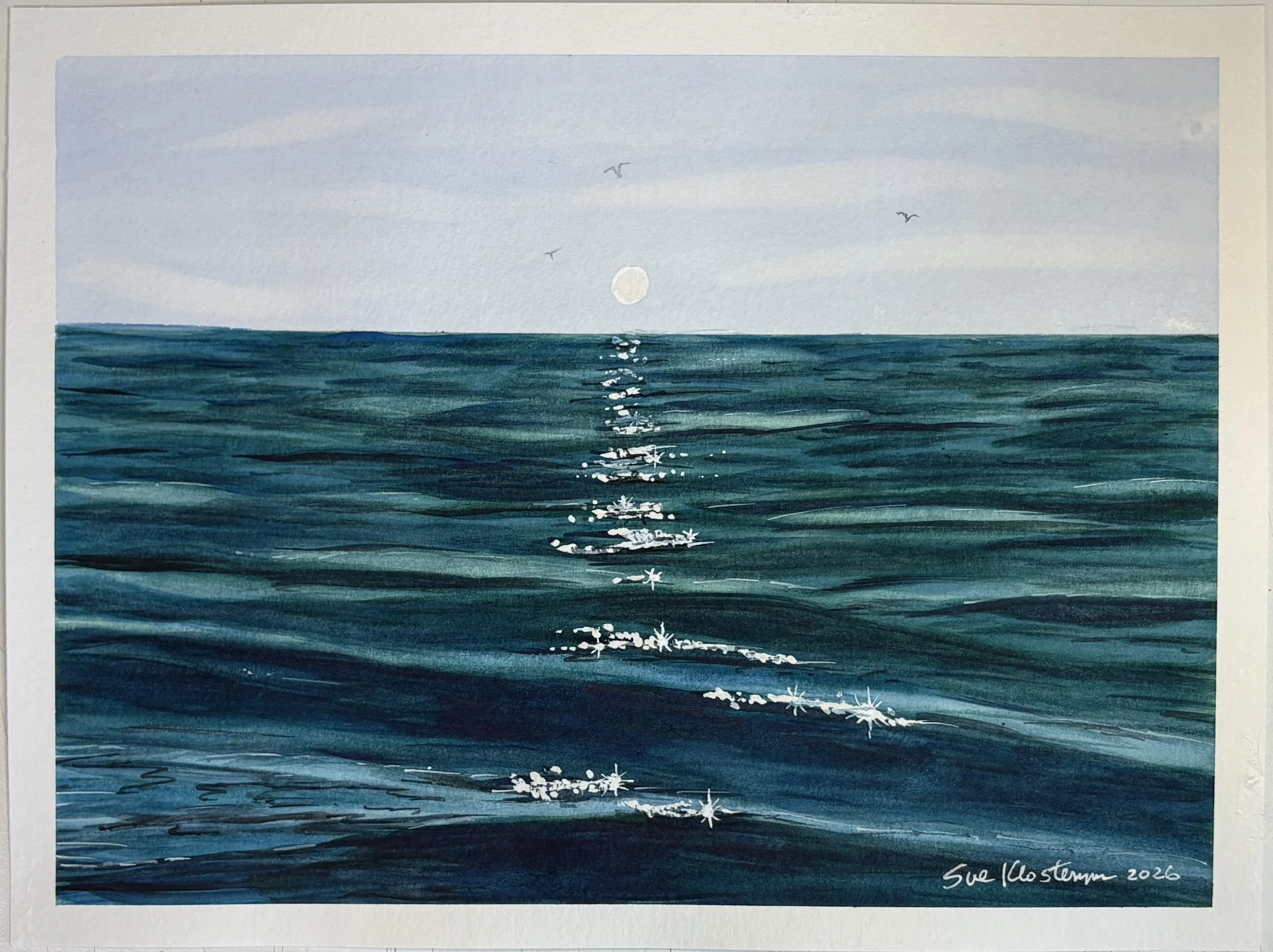 A watercolor painting of the ocean with an overcast sky. The sun is partially obscured, reflected in the water, and three birds are flying above the water. The artist's signature is in the bottom right corner, reading 'Sue Klosterman 2026'.