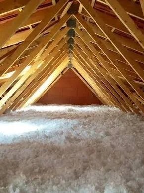 Interior de un ático en construcción con estructura de madera y aislamiento en el suelo.