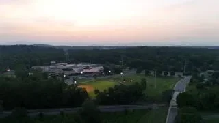 A landscape view of a park or sports field area with trees and pathways during sunset or dawn.