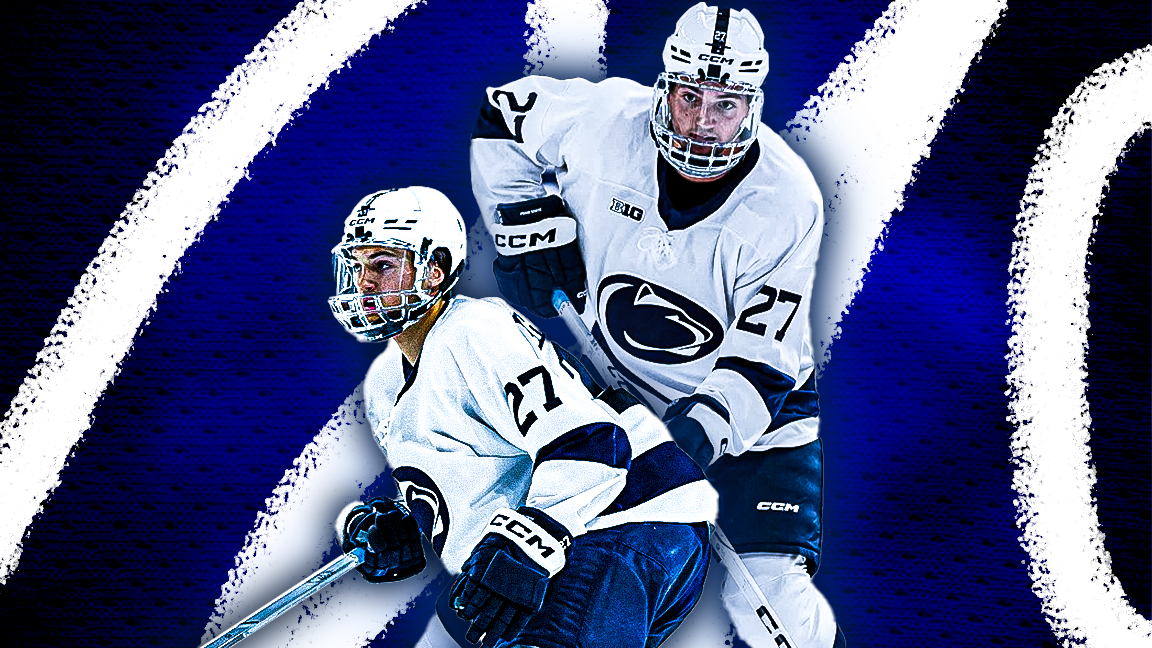 Two ice hockey players from Penn State team wearing white jerseys and helmets on blue ice rink.