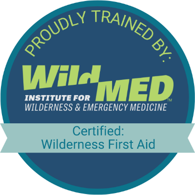 Badge showing WildMed Institute for Wilderness and Emergency Medicine certification as Wilderness First Aid, with green and blue colors.