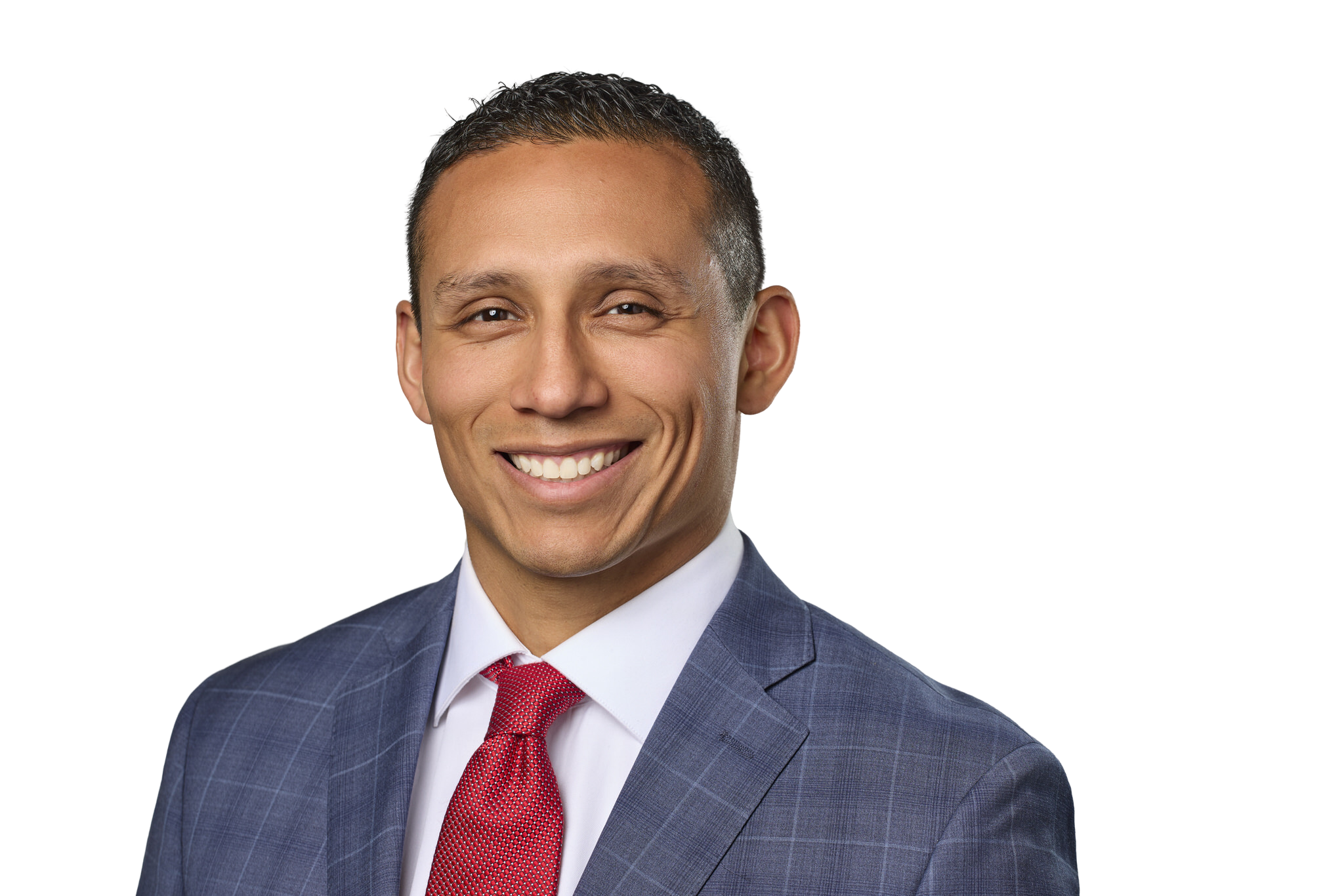 Portrait of a smiling man wearing a dark blue checkered suit, white shirt, and red tie, with short dark hair.