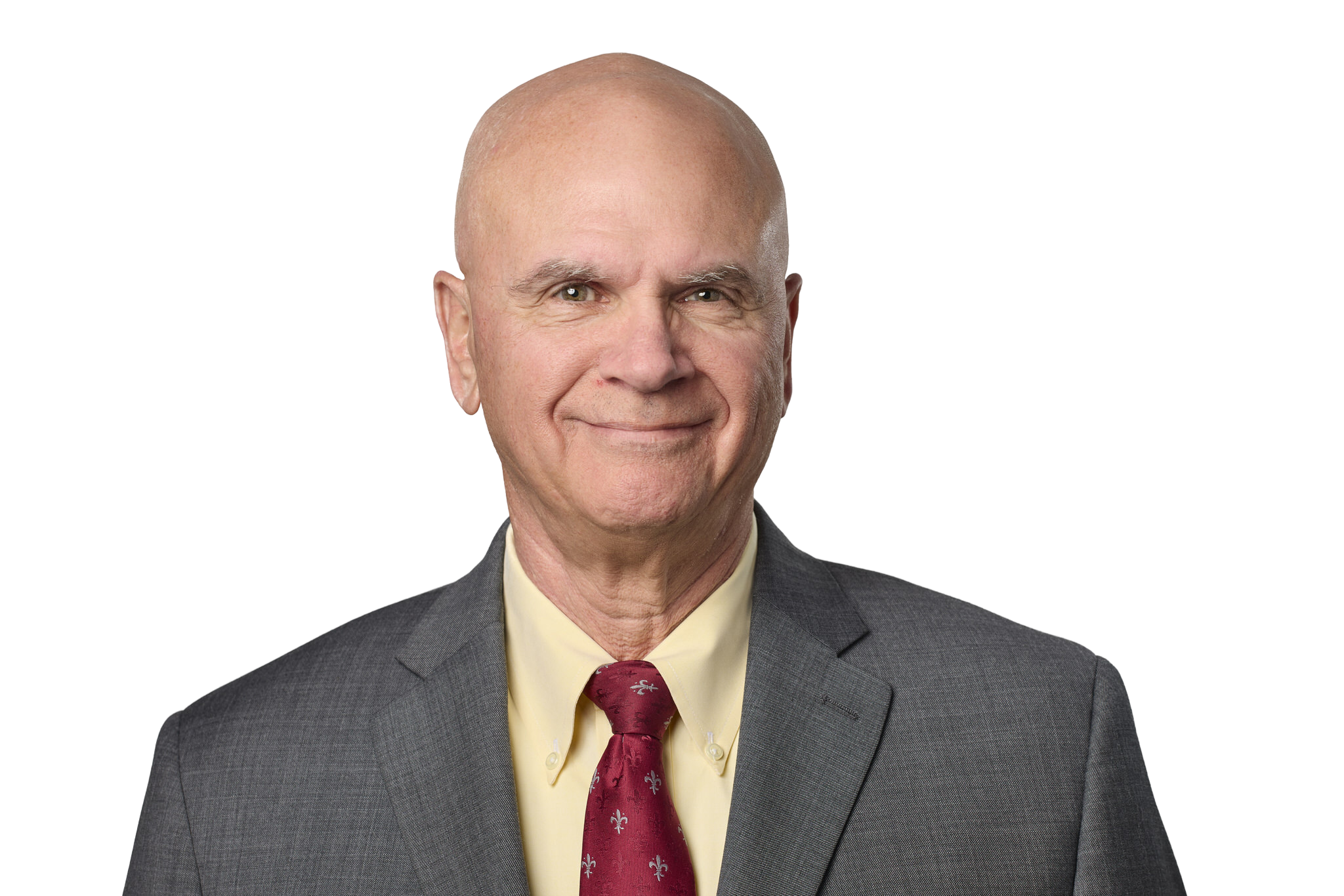 A middle-aged man with a bald head smiling in a professional portrait, wearing a dark gray suit, light yellow shirt, and red tie with white floral patterns.