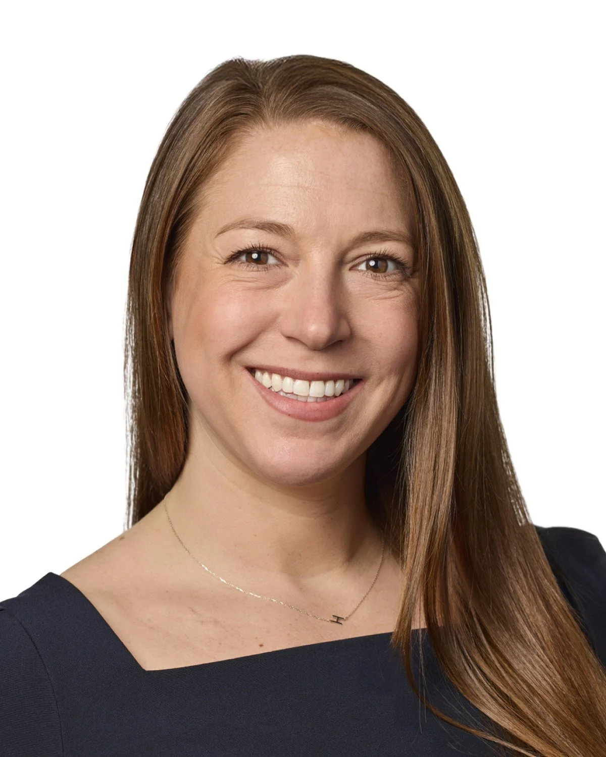 Headshot of a smiling woman with brown hair, wearing a dark top and a delicate necklace, against a white background.