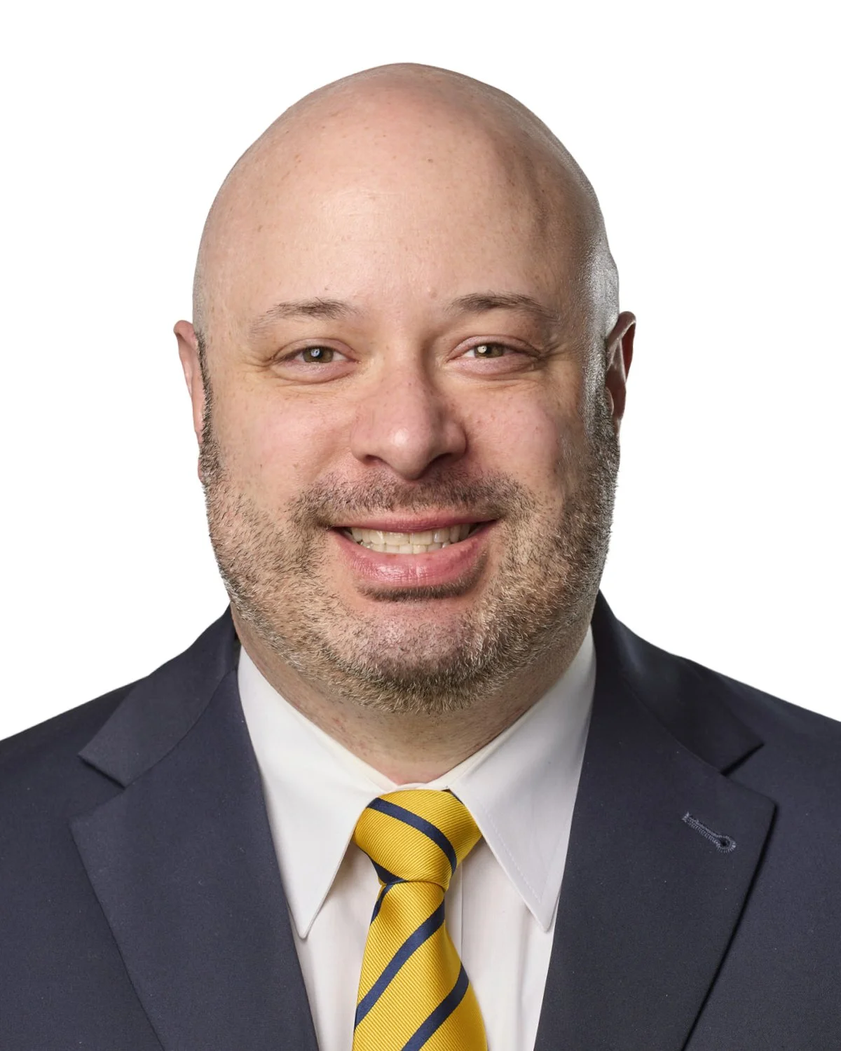 Headshot of a man with a bald head and beard, wearing a black suit, white shirt, and yellow striped tie, smiling against a white background.