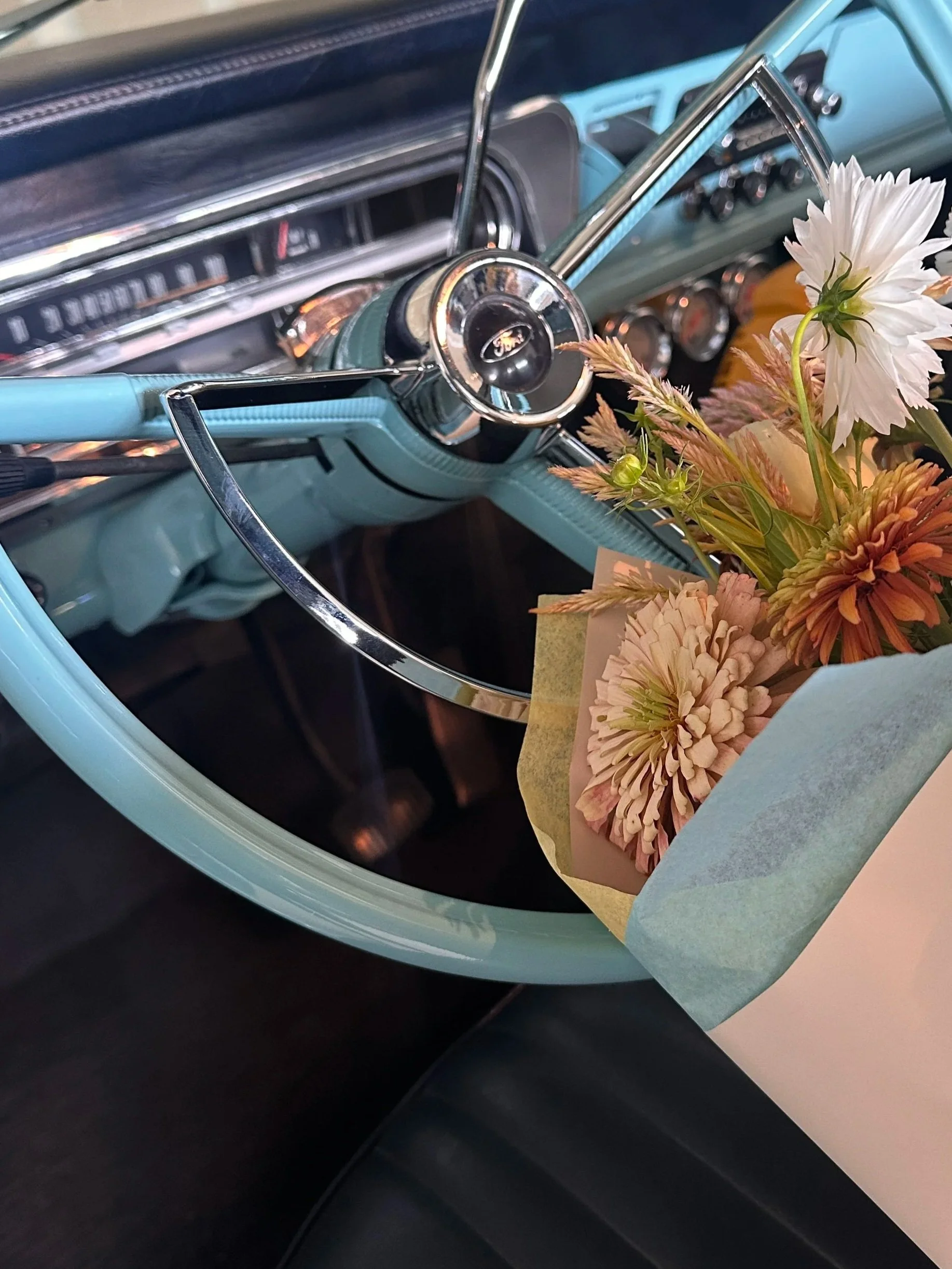 Interior of a vintage car with a bouquet of flowers on the dashboard.