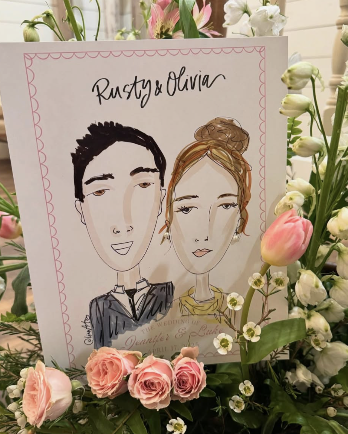 A wedding sign featuring a cartoon illustration of a couple, Rusty and Olivia, surrounded by pink and white flowers.