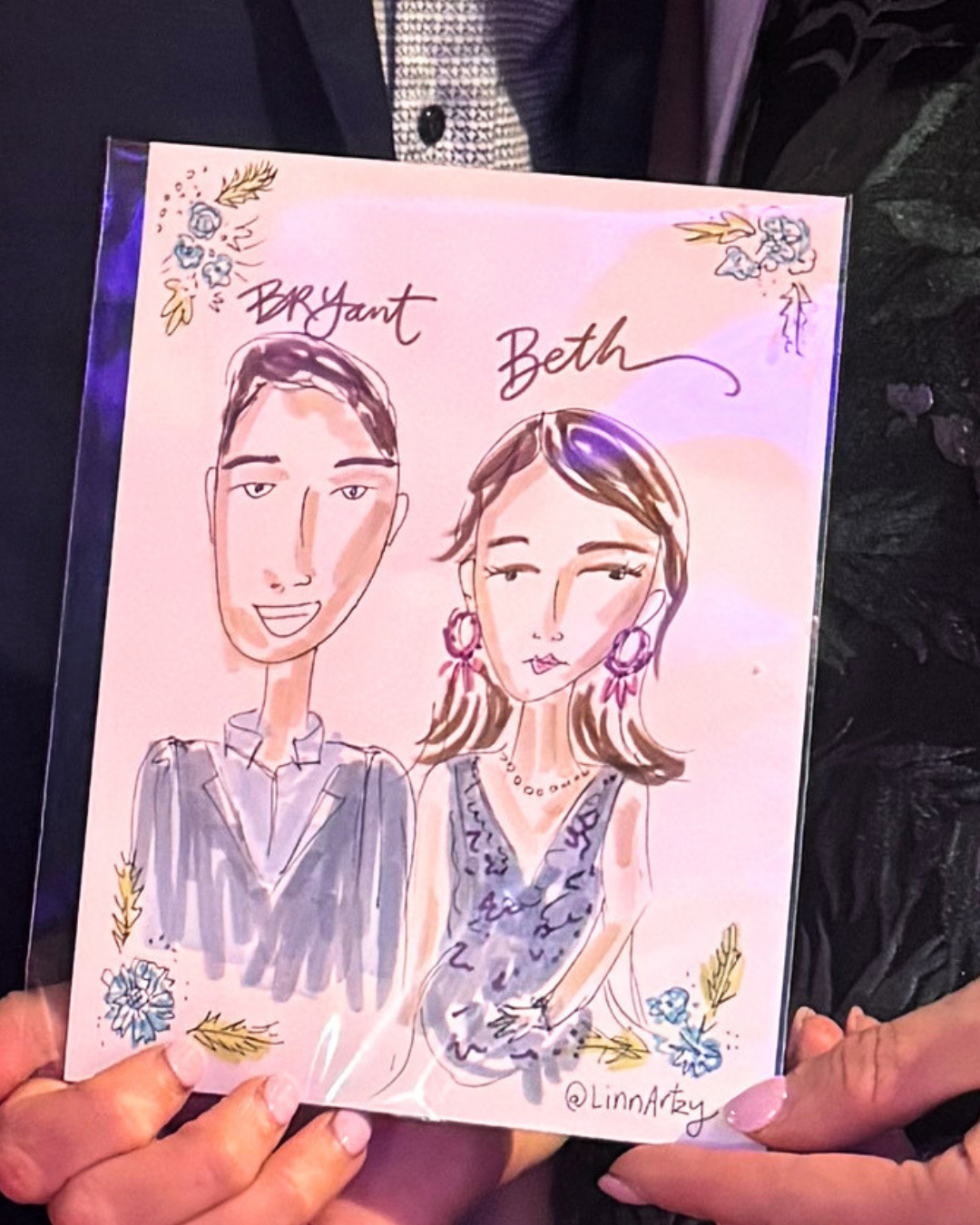 A caricature drawing of a man and a woman, labeled Bryant and Beth, surrounded by decorative floral and leaf accents, with the artist's signature @LinnAsty.