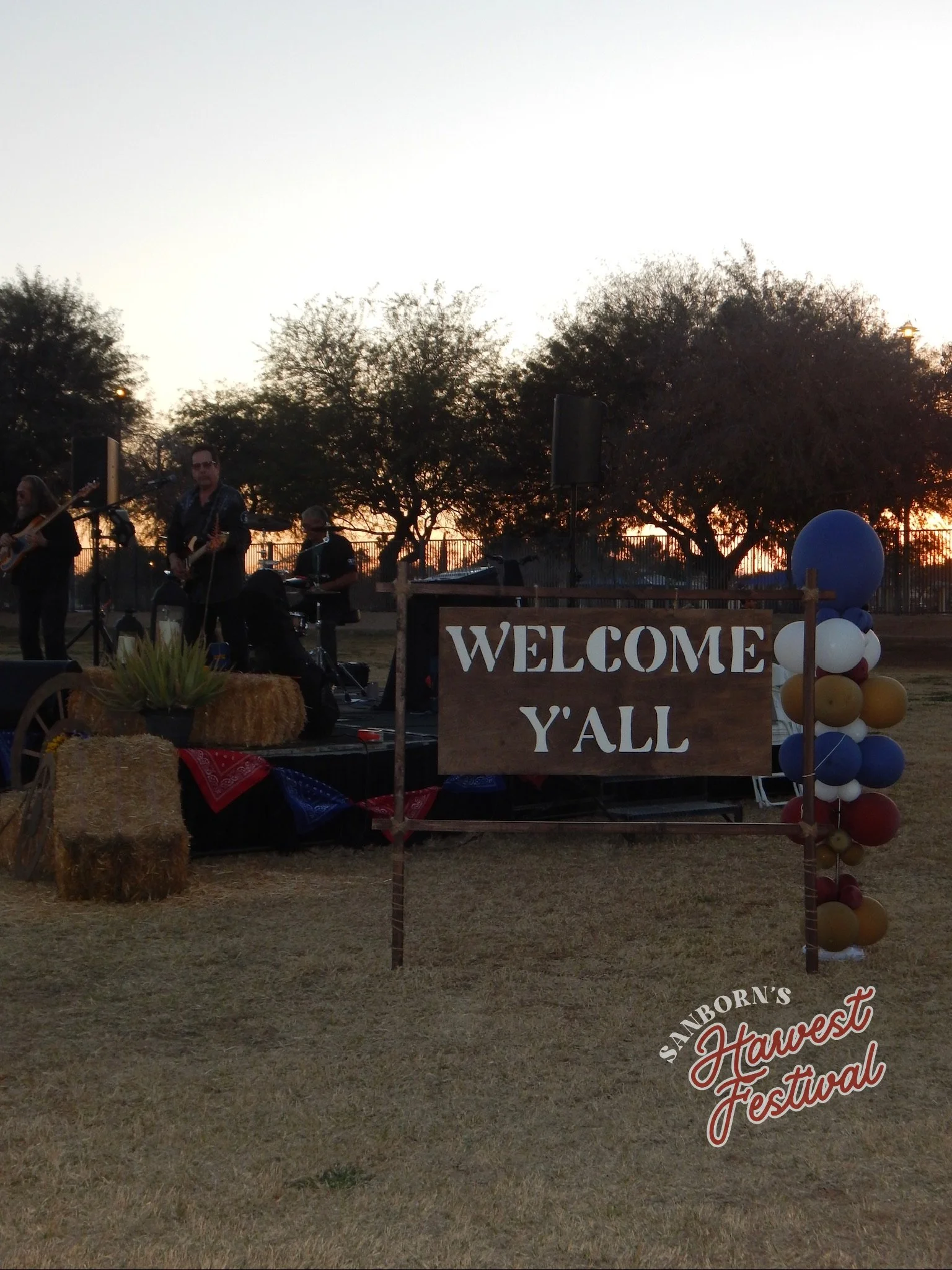 Outdoor stage with a band performing at a festival during sunset. A 
