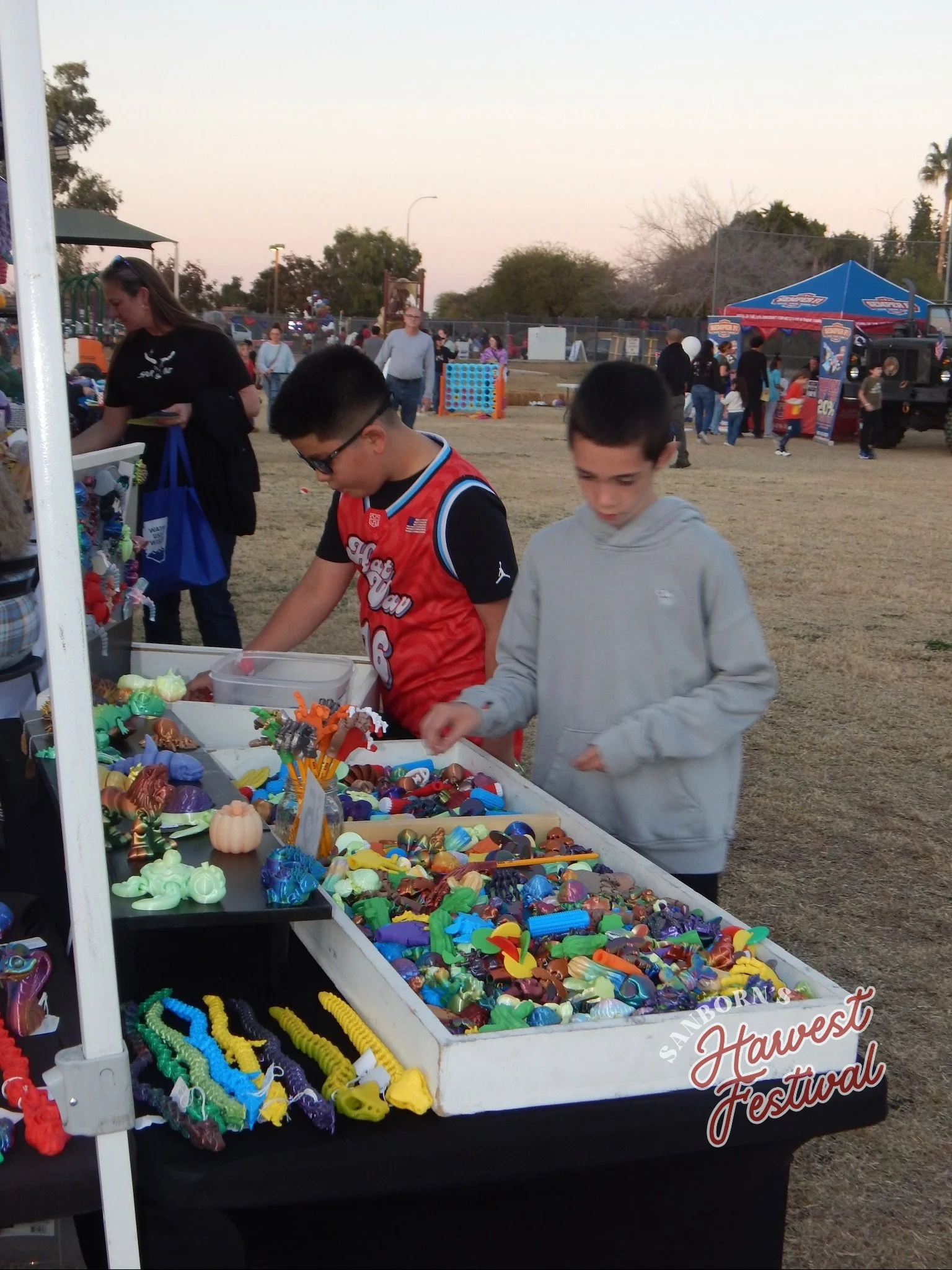Children browsing a toy stall at the Harvest Festival, with colorful toys on display.