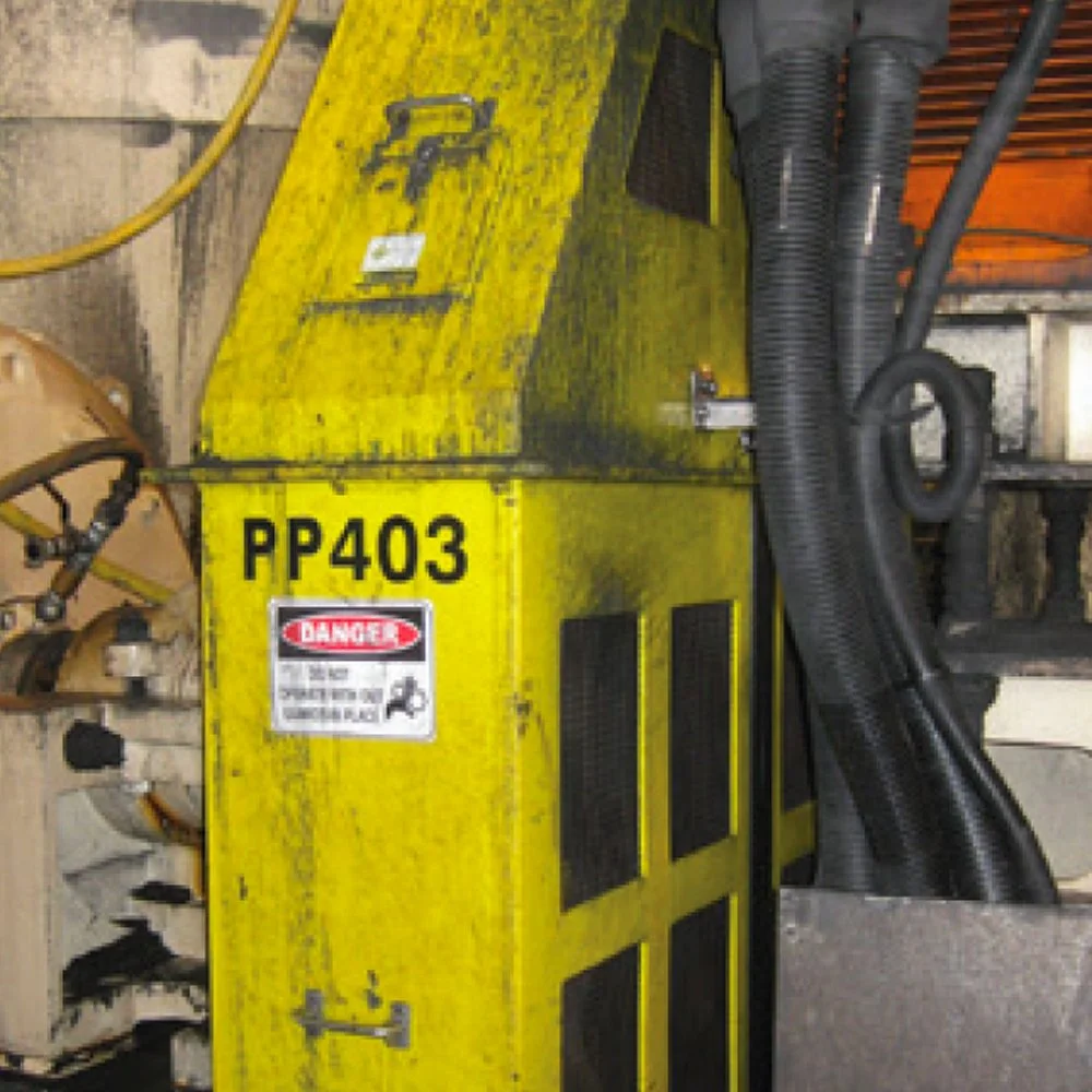 A yellow industrial machine labeled RP403 with black vents and a red and white caution sticker, surrounded by black hoses in a workshop.