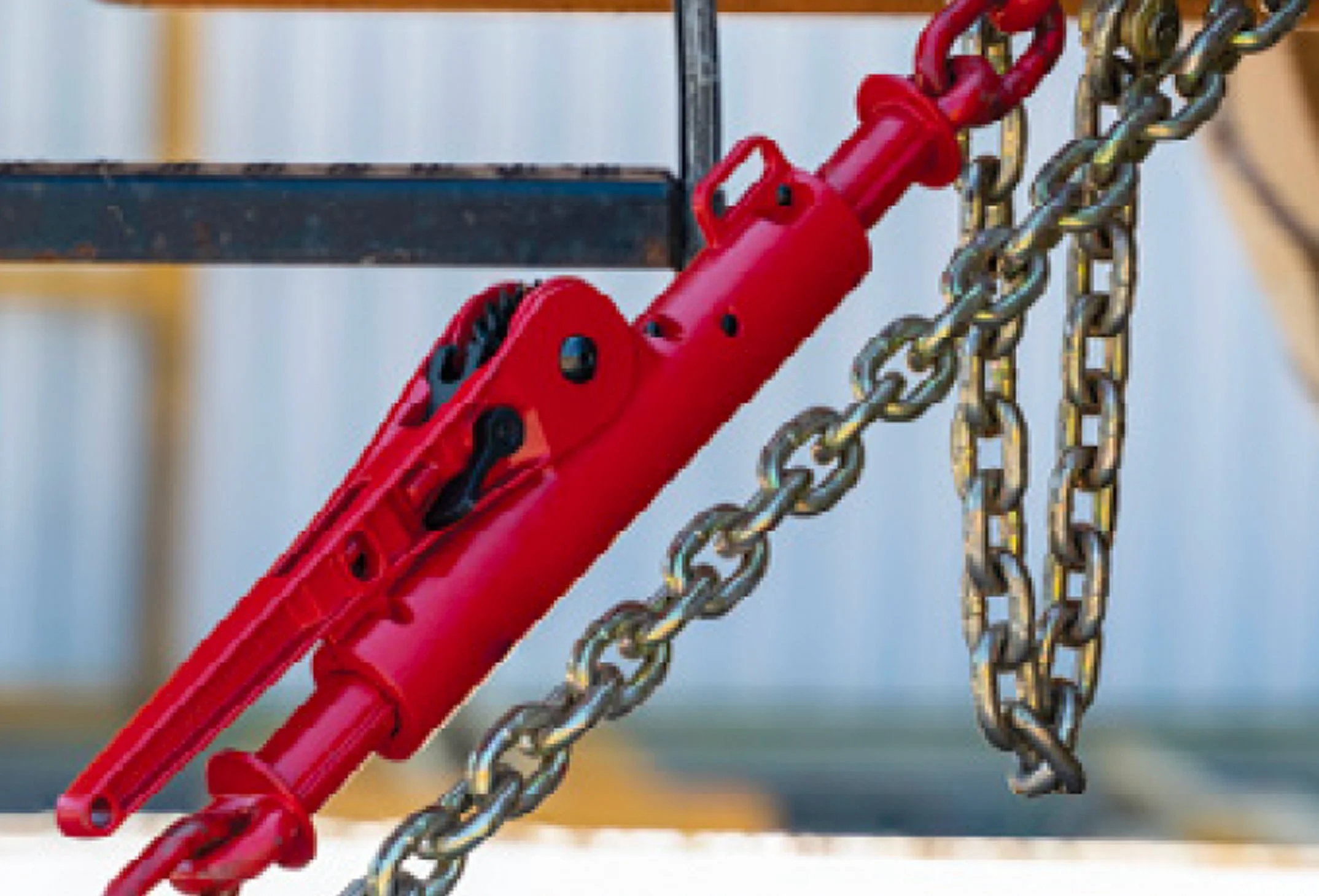 A red industrial hydraulic cylinder attached to a metal chain.