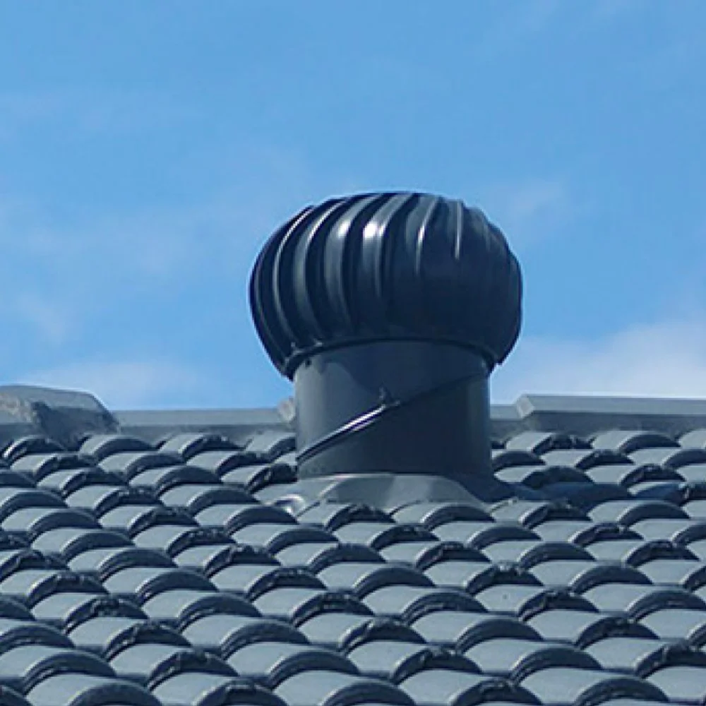 Close-up of a black chimney vent on a tiled roof with a blue sky in the background.