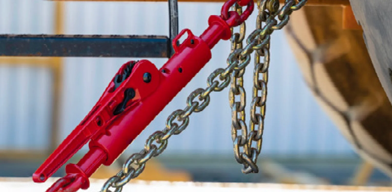 Red hydraulic rescue tool, also known as the Jaws of Life, attached to metal chains, used by emergency personnel for vehicle extrication.