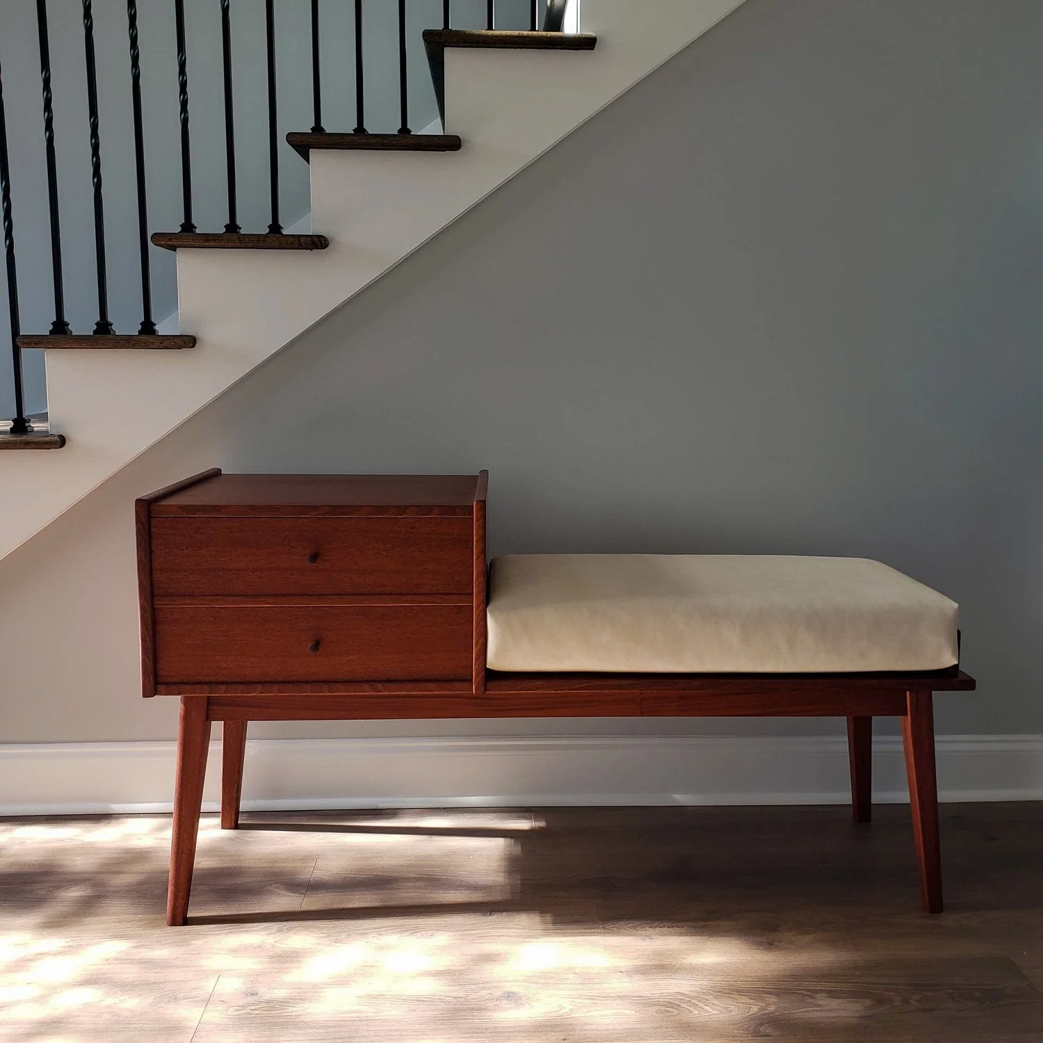Mid-Century Modern Sapele Gossip Bench beneath a staircase in a residential interior