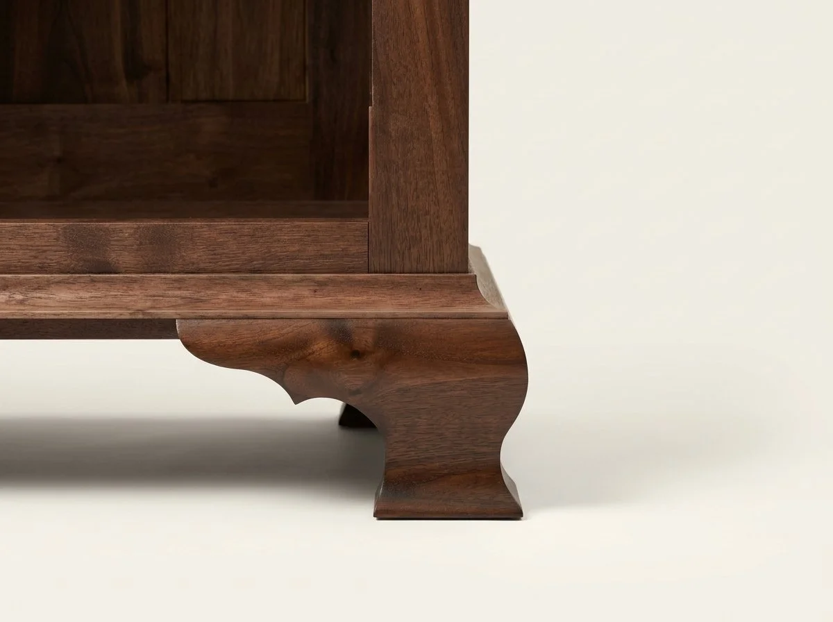 Close-up of the shaped walnut foot and lower molding on the handmade Masterworks china cabinet.