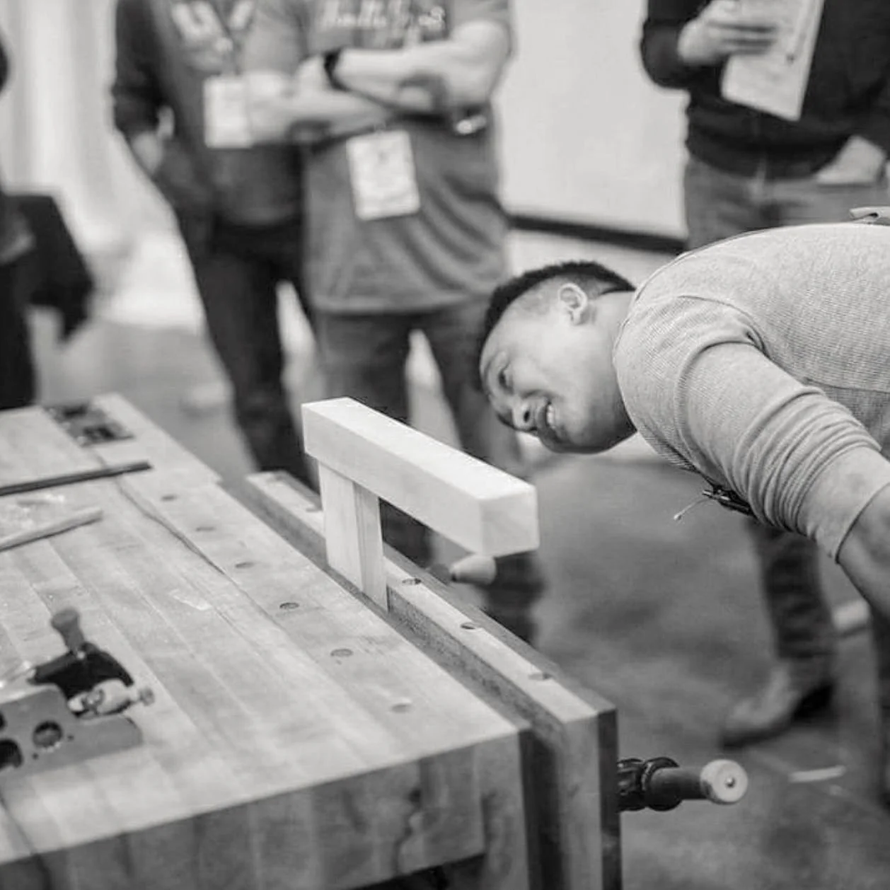 Woodworking instructor examining a furniture joint during a hands-on workshop demonstration.