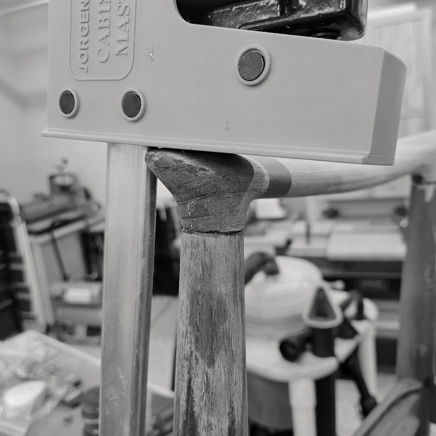Close-up of a Hans J. Wegner JH 503 teak chair frame secured with a clamp during restoration work.